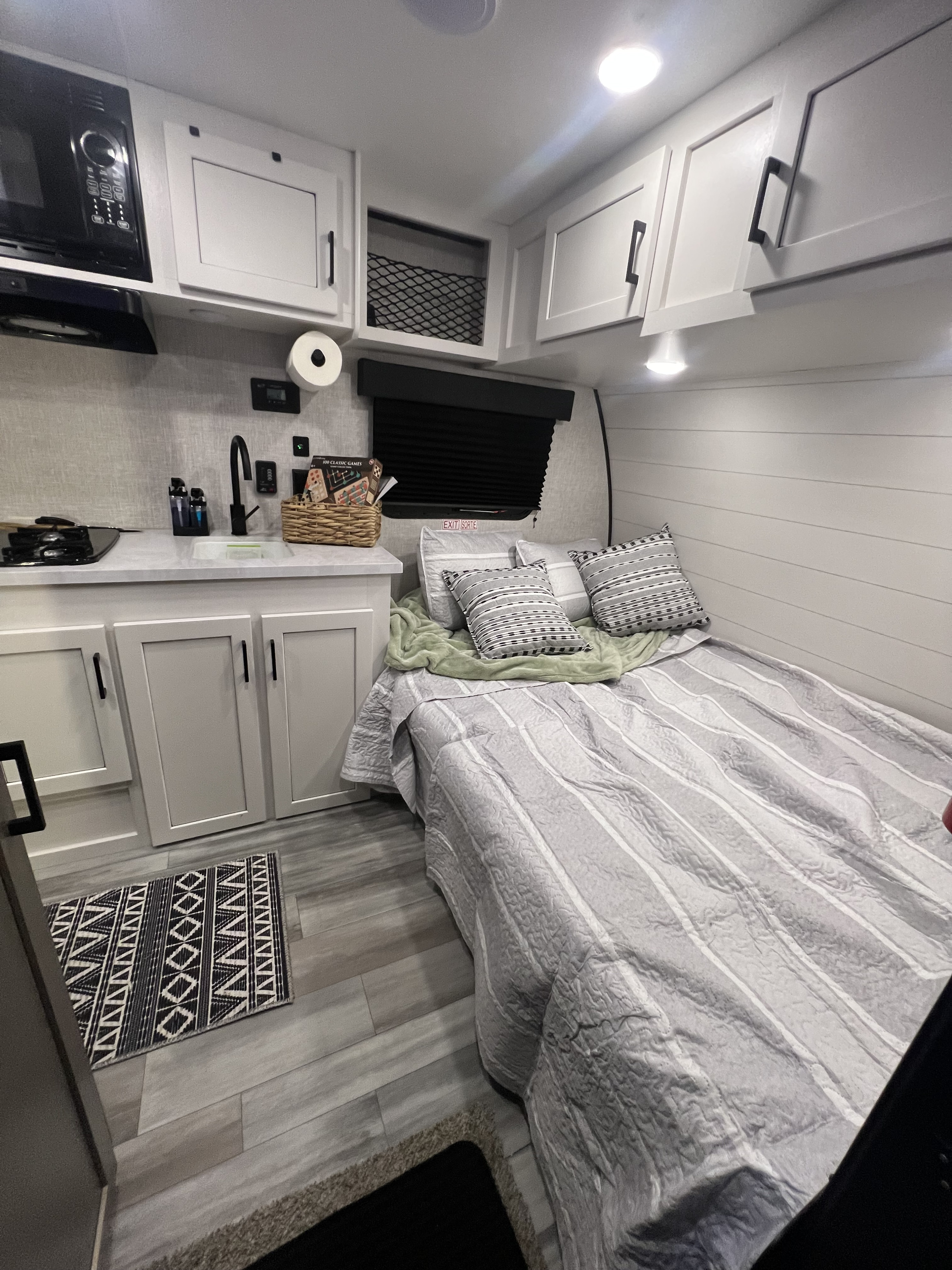 Cozy RV rental interior featuring a modern kitchen setup with microwave, sink, and a comfortable bed.. Jayco Jay Flight SLX Baja Edition 2024