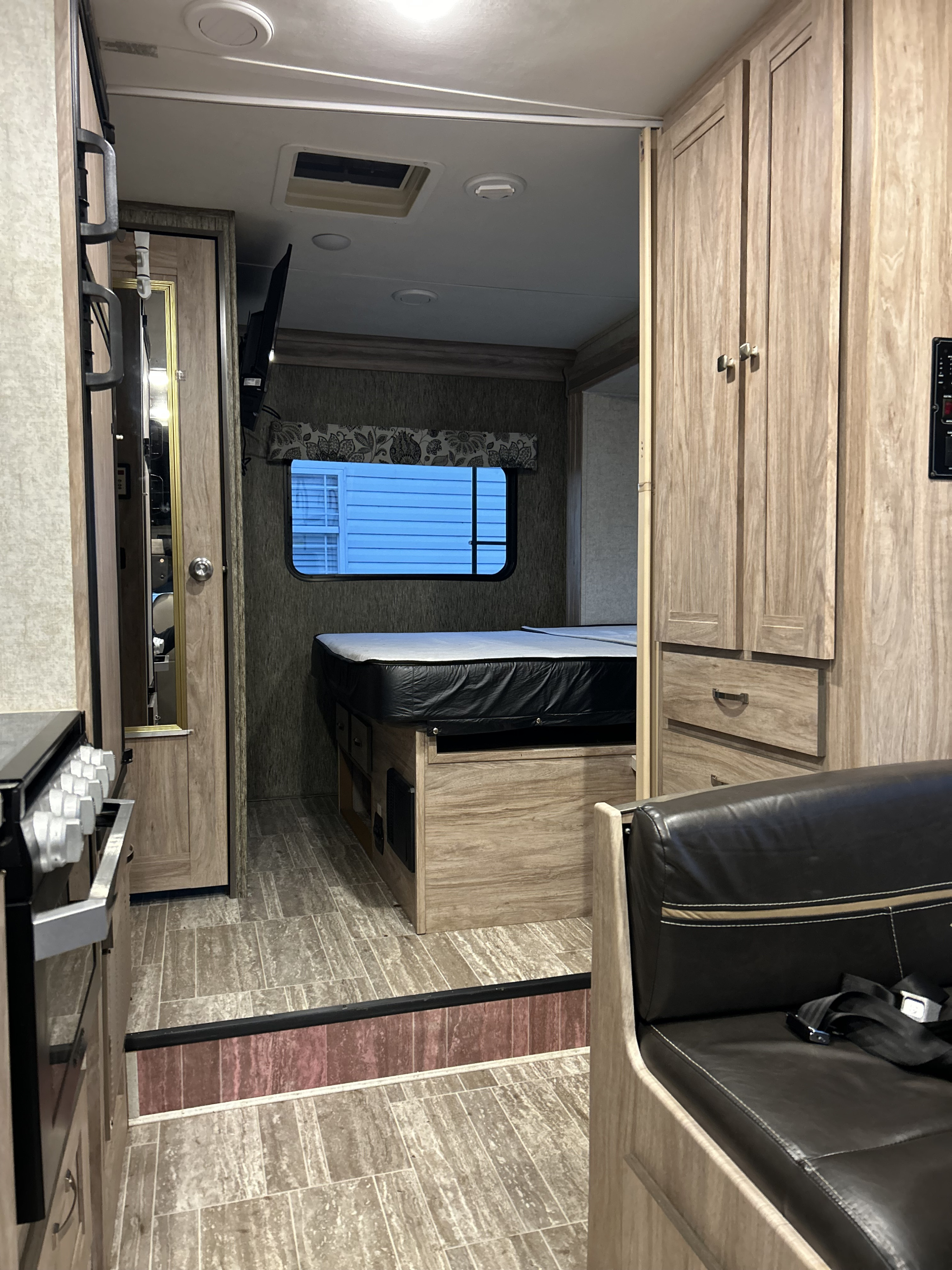 RV rental interior showcasing the bedroom, kitchen, wood cabinets, and dinette with a seatbelt. Ideal for road trips.. Forester Forester Motorhome 2019