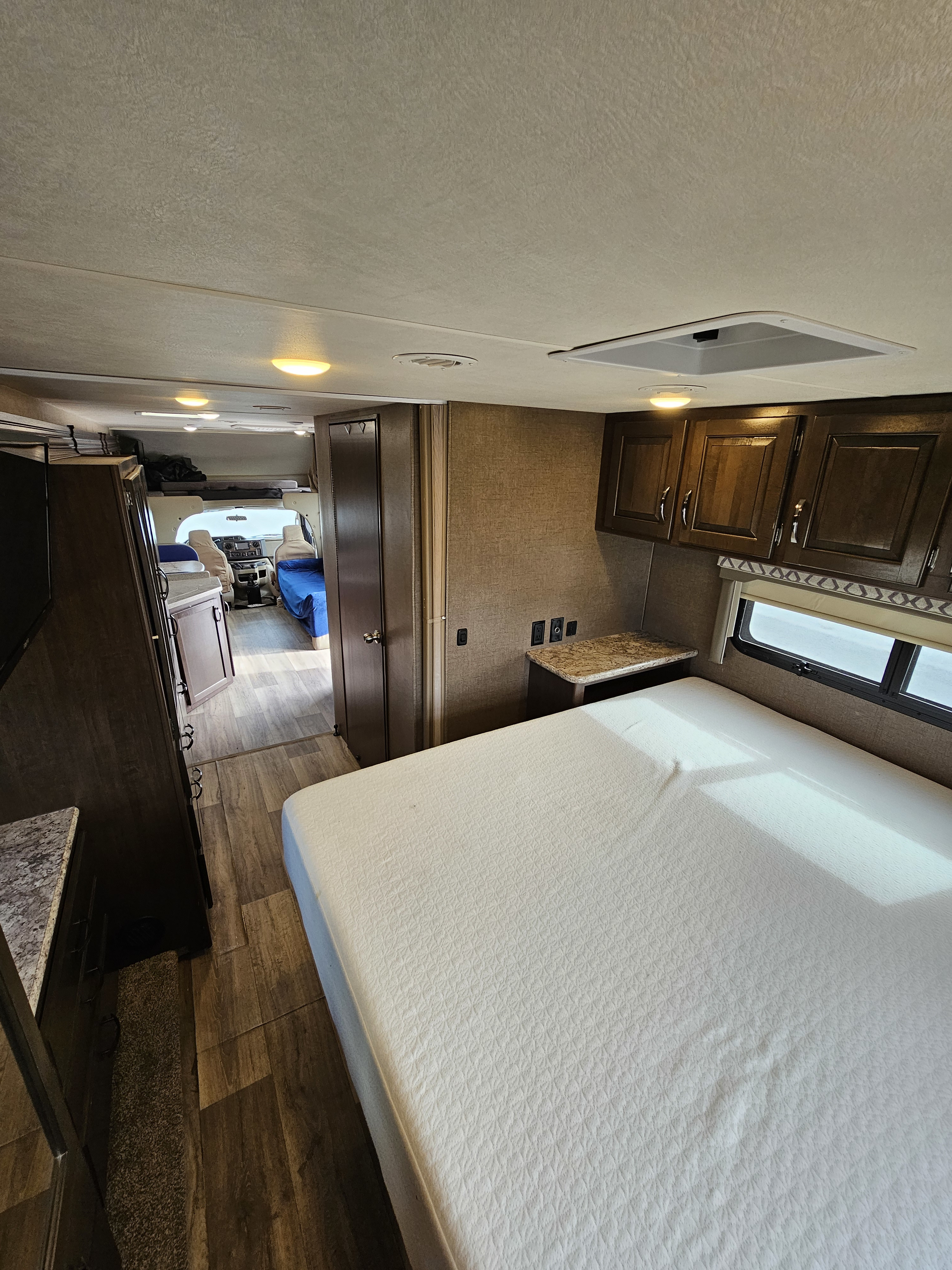Step inside this RV rental: interior view from bedroom past bed to front cab and living space.. Thor Four Winds 2019