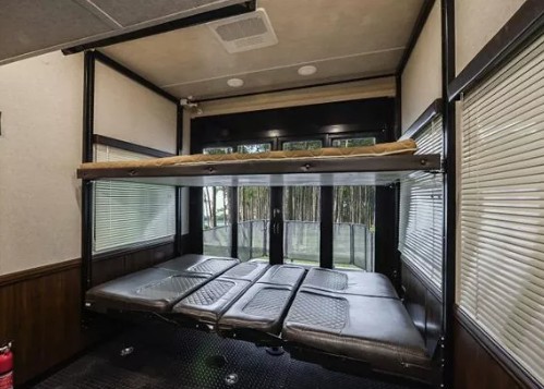 This RV rental shows a versatile interior with a top bunk and a convertible lower bed/seating setup, overlooking nature.. Heartland Cyclone 2020