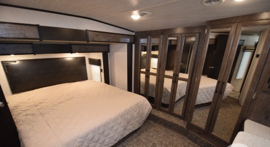 Experience comfort on the road in this spacious RV rental bedroom, featuring a large bed and mirrored closets, perfect for your travels.. Heartland Cyclone 2020