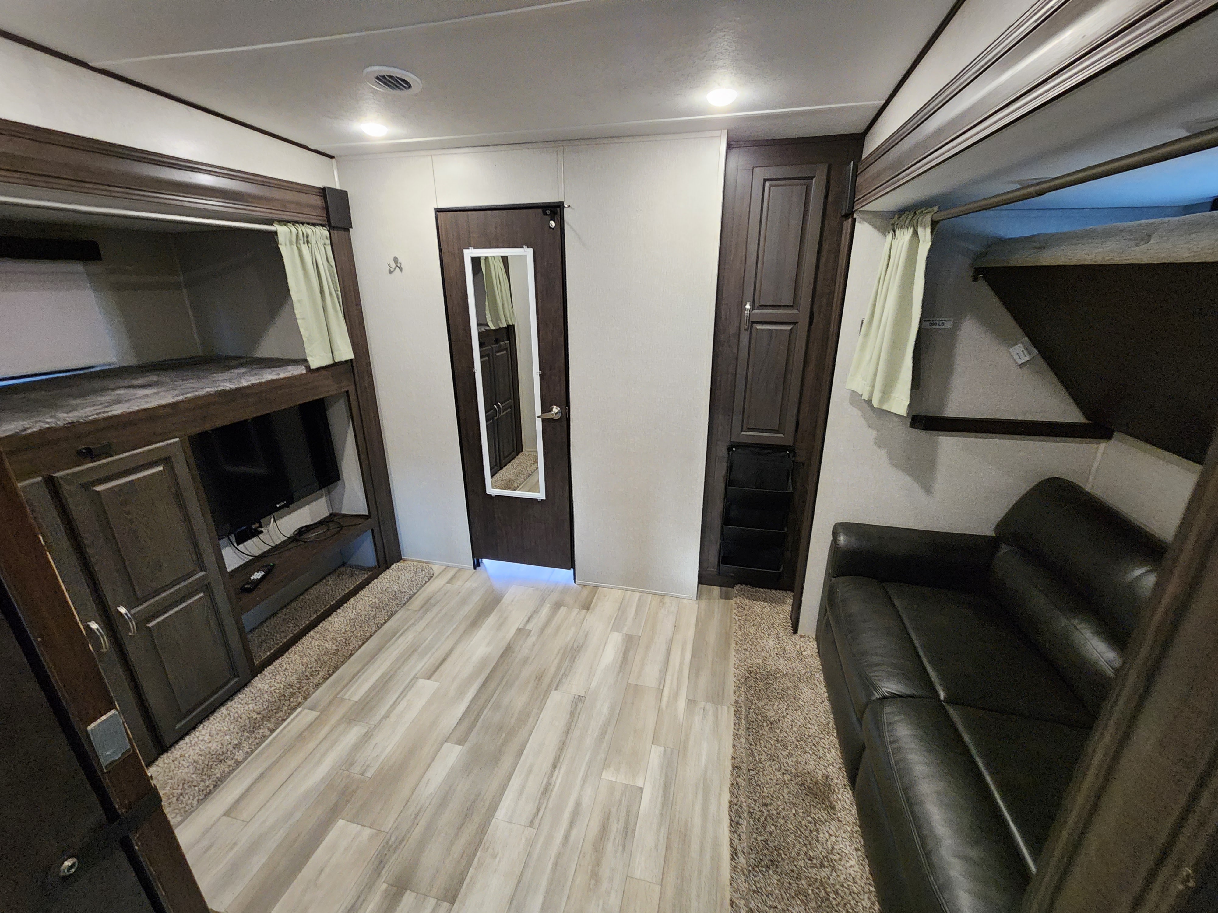 Spacious RV rental interior featuring bunk beds, a TV, and a cozy living area with a couch.. Forest River Shasta Phoenix 2021