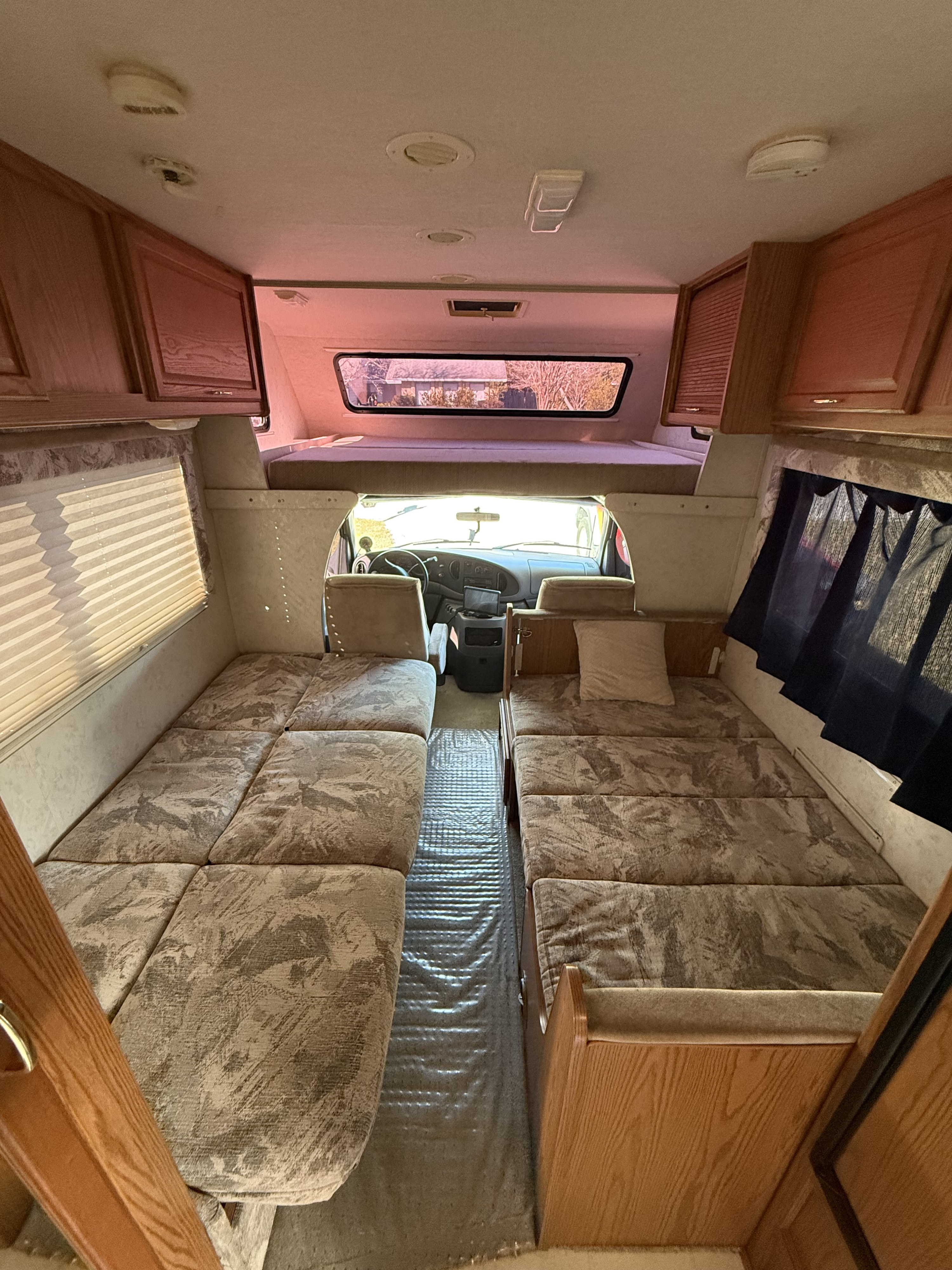 Spacious RV rental interior with parallel beds, overhead bunk, and front cabin view, ideal for travel.. Winnebago Minnie 2000