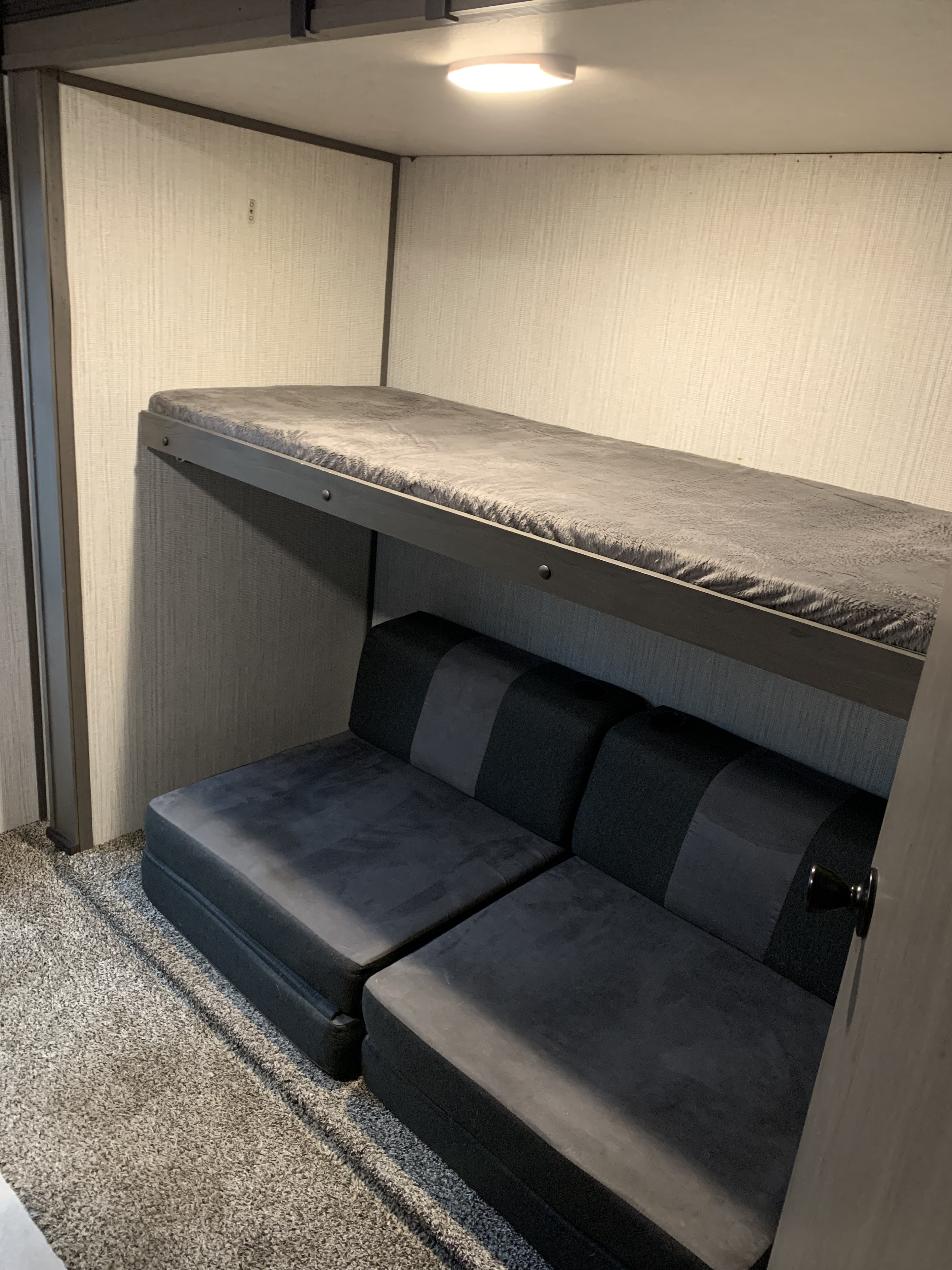 This RV rental features a cozy bunk bed with grey bedding over versatile modular seating, perfect for a family adventure.. Cruiser Rv Corp embrace el 310 2020