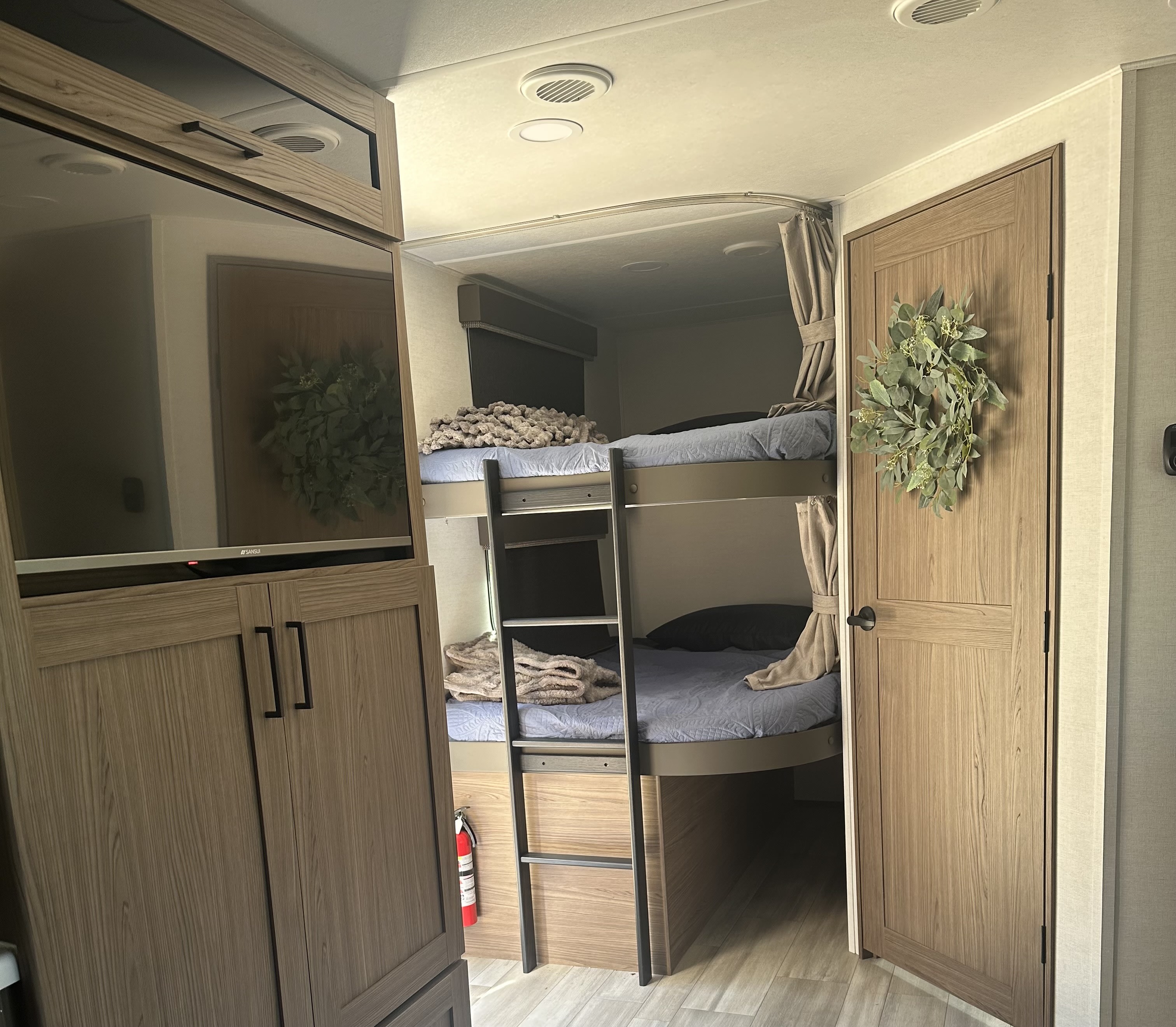 Spacious RV rental interior featuring cozy bunk beds, a TV, and wood-toned cabinets. Ideal for family travel.. Alliance RV Delta 251BH 2024