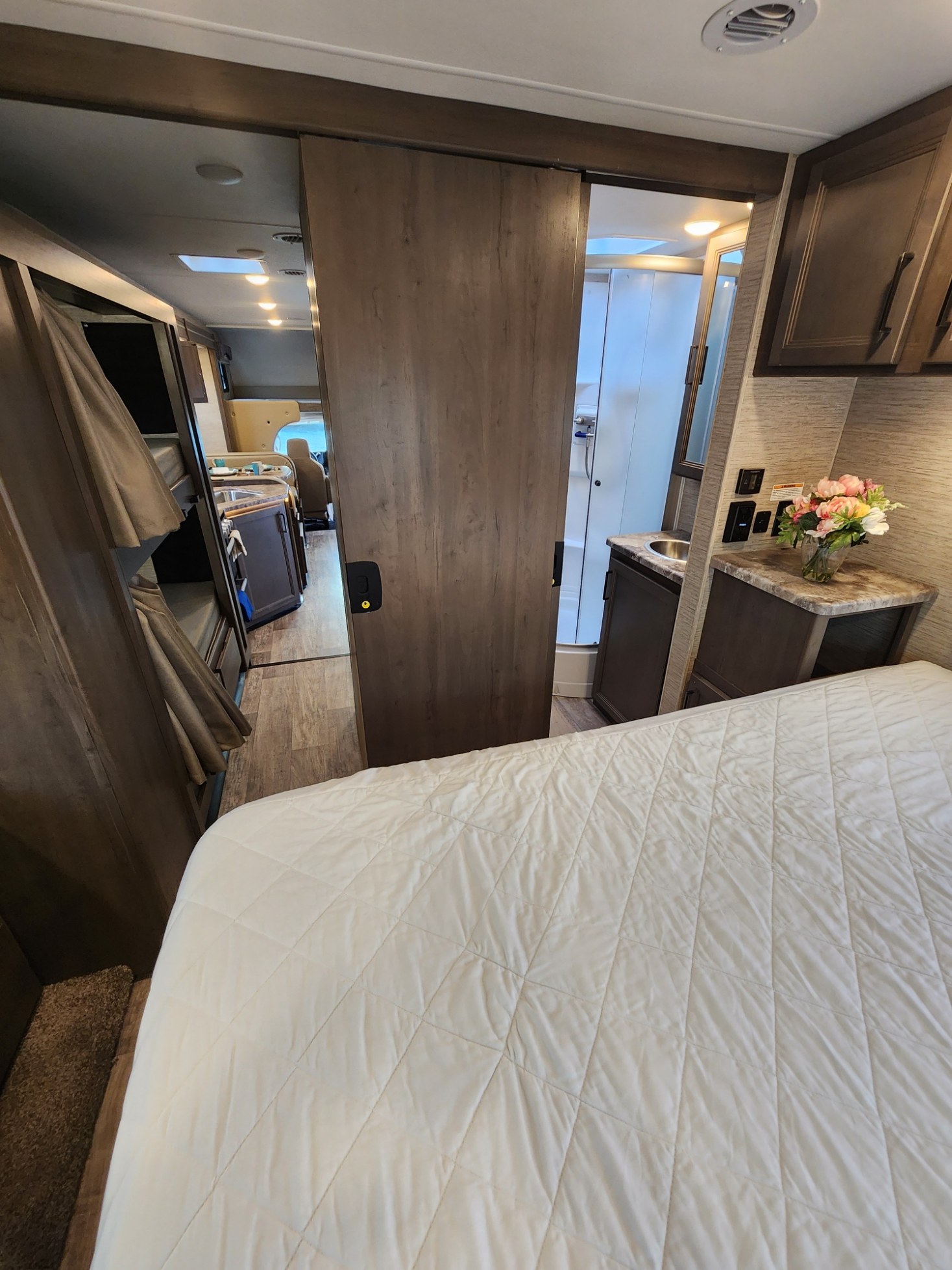 RV rental interior: View of a comfortable bedroom, sliding door to bunks, and bathroom; kitchen/dining visible beyond.. Thor Motor Coach Chateau 2023