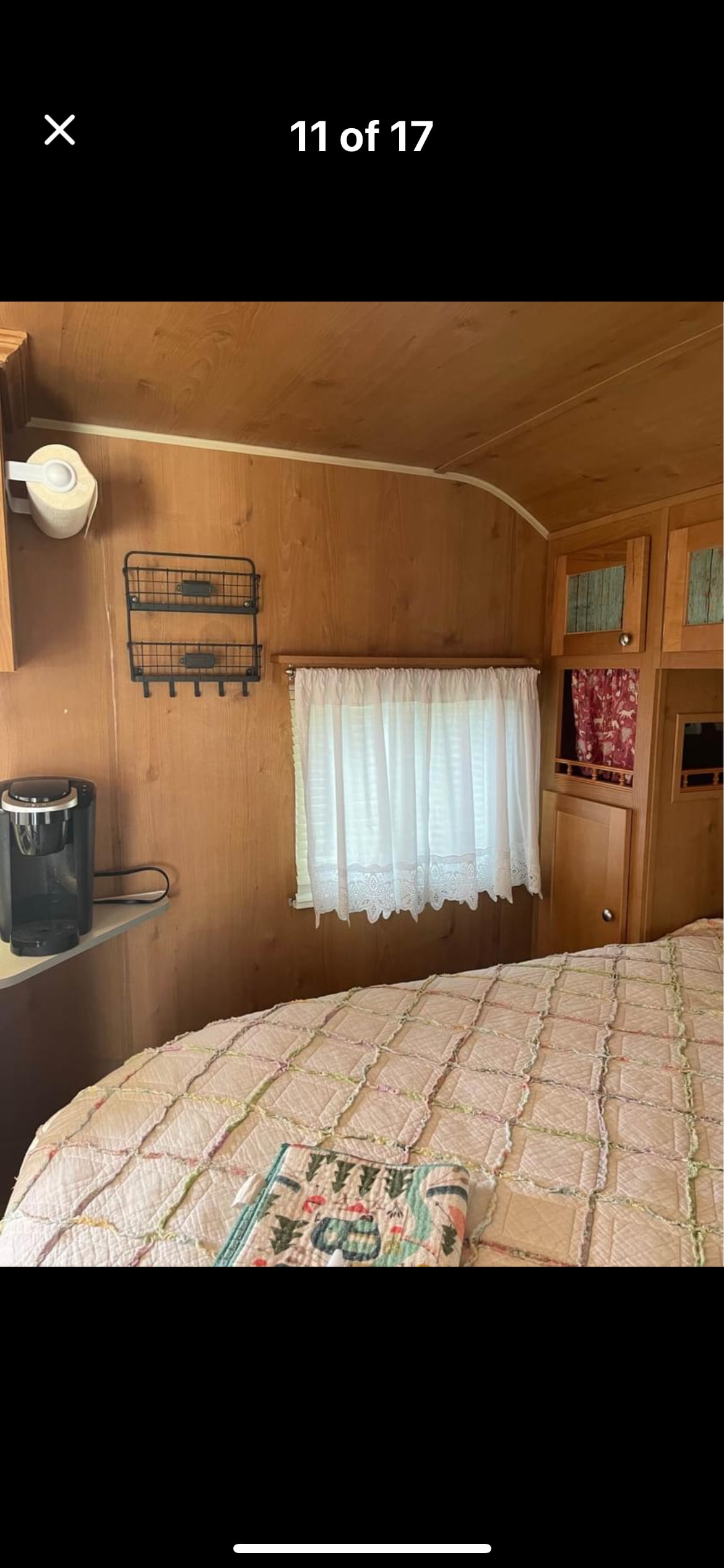 Inviting RV rental interior: bedroom area with a cozy quilted bed, wooden walls, window, and convenient coffee maker.. Riverside Travel Trailer Retro 2017