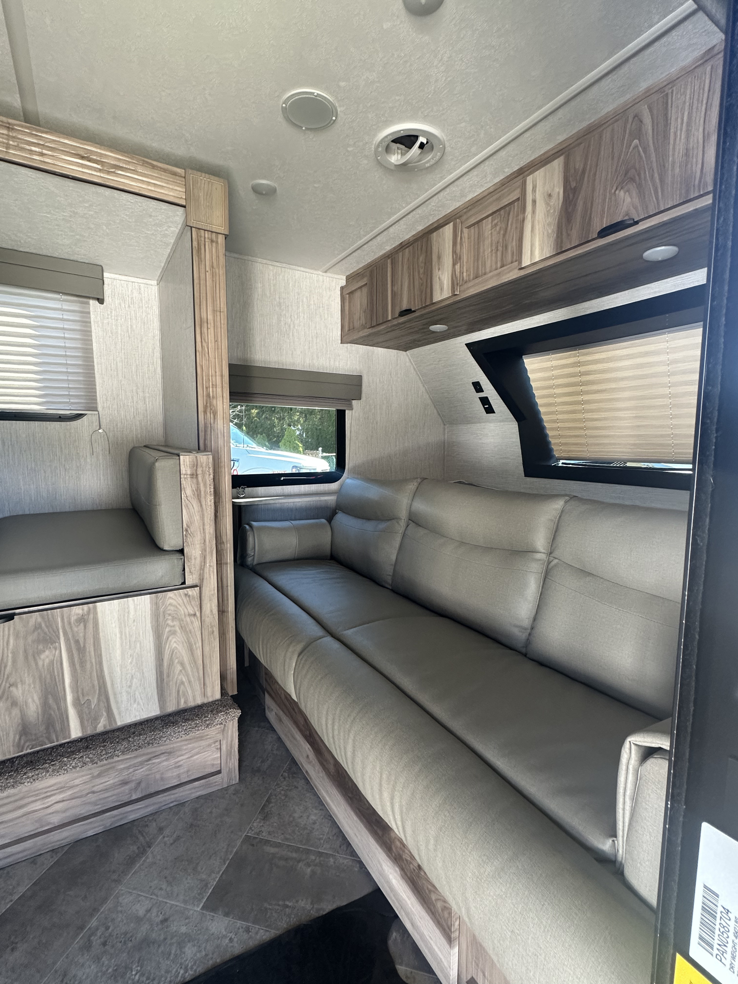 Inviting RV rental interior featuring a long sofa, dinette, wood-grain cabinets, and modern finishes.. Palomino Real Lite Mini 2022