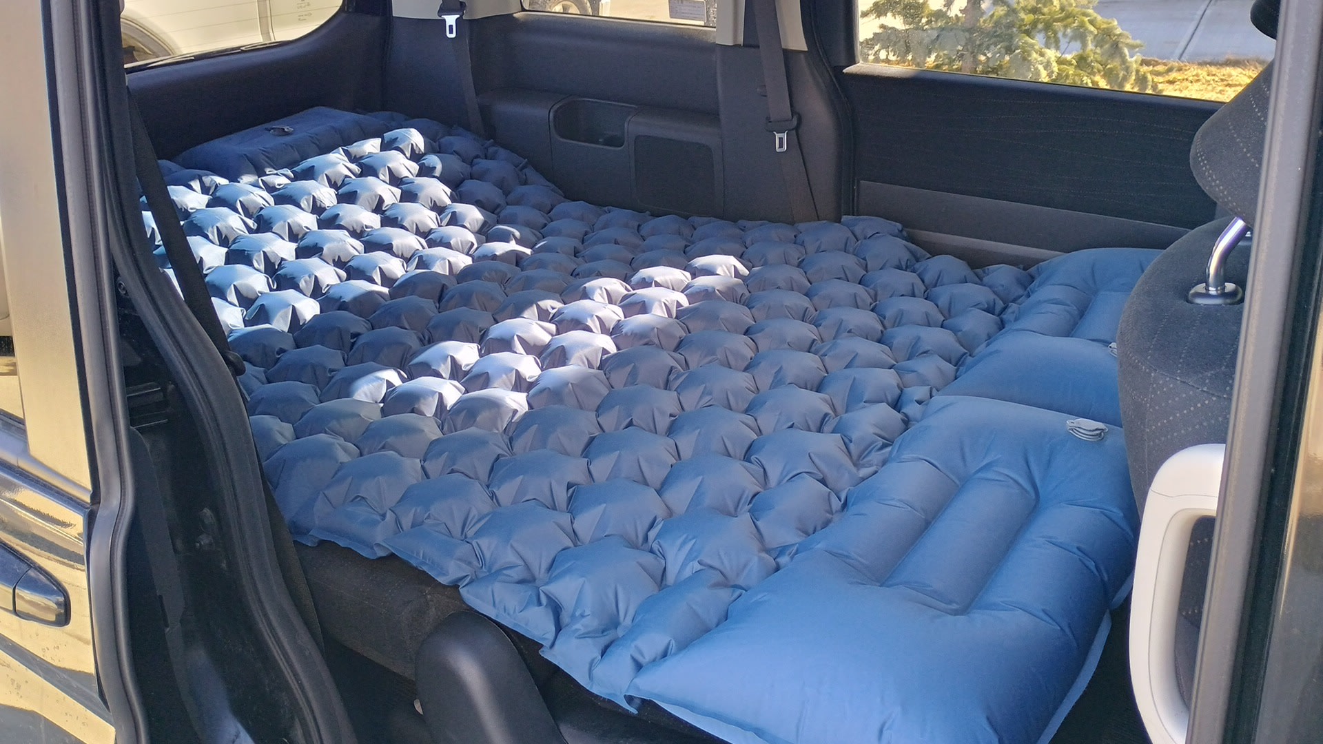 Car transformed for comfortable sleep: a blue bubble air mattress and pillow in the rear, ideal for RV rental alternatives.. Universal Transformer 2009