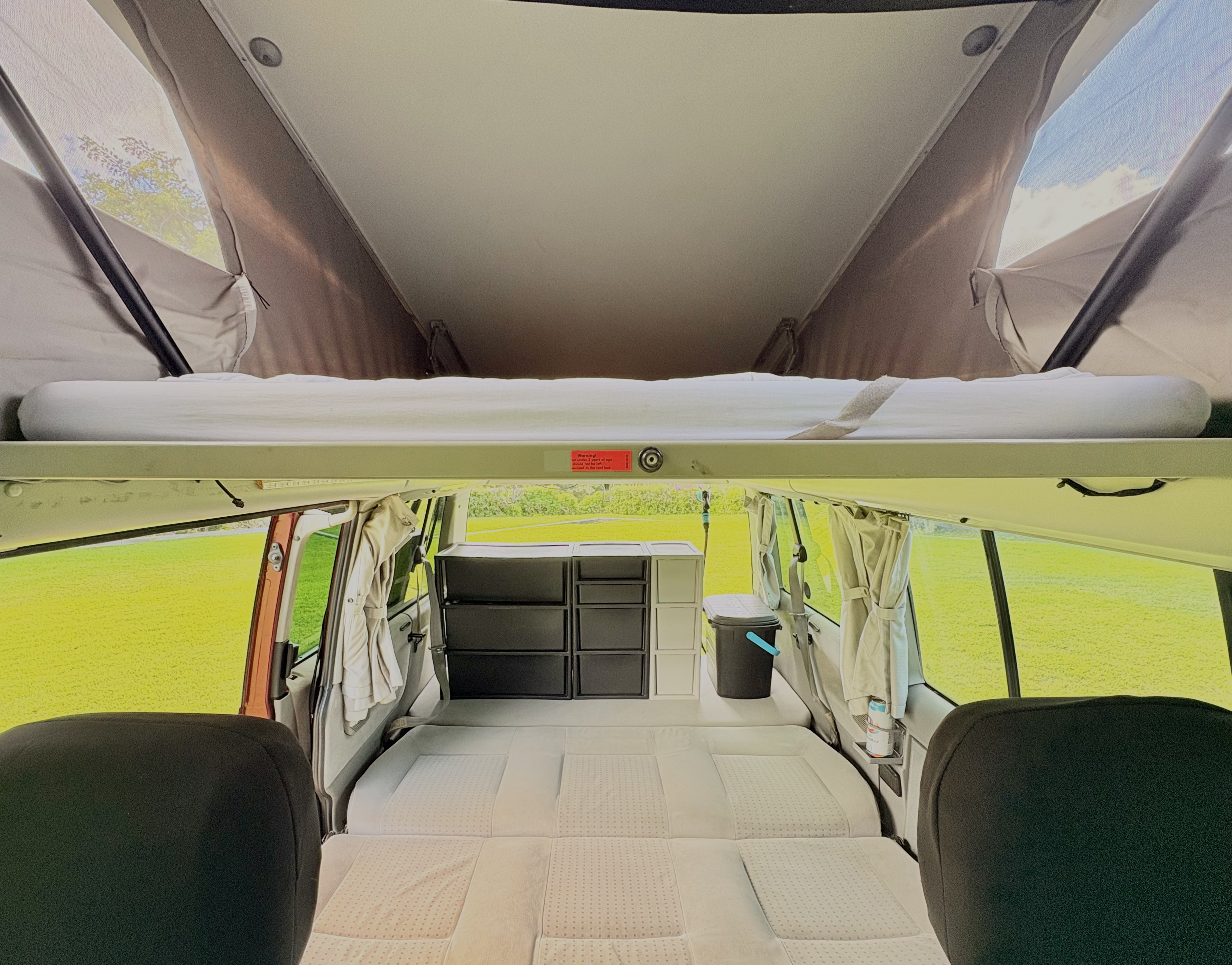 RV rental interior: pop-top roof bed, convertible lower bed, & storage. Views of green fields from the comfort of your camper.. Volkswagen T4 Transporter 2002