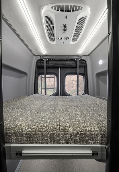 Experience comfort in this RV rental camper van: a plush rear bed, AC unit, and bright LED lighting for scenic travels.. Winnebago Revel 2025