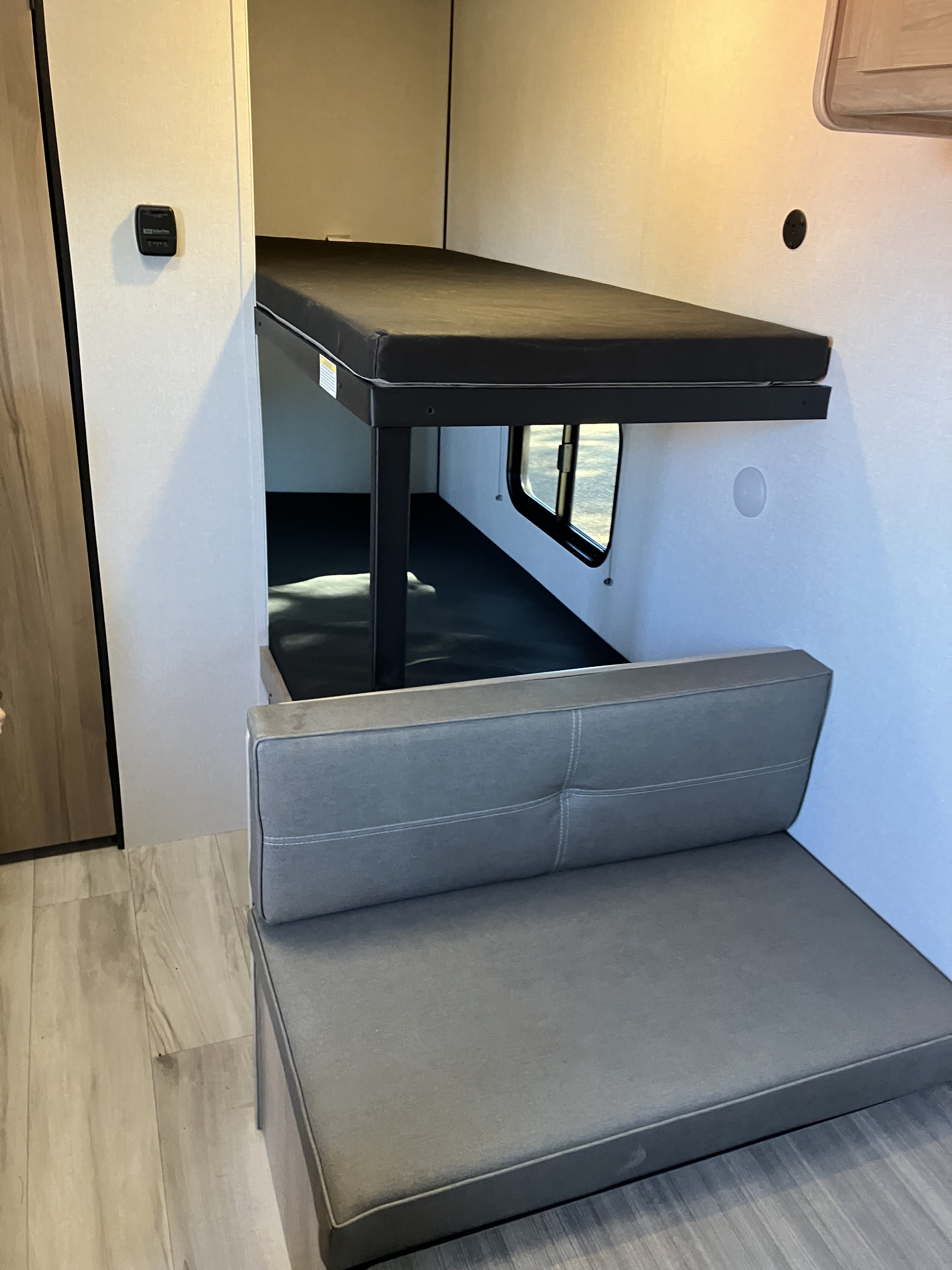 RV rental interior shows bunk beds, a gray cushioned dinette seat, and light wood flooring.. Coleman 17B 2025