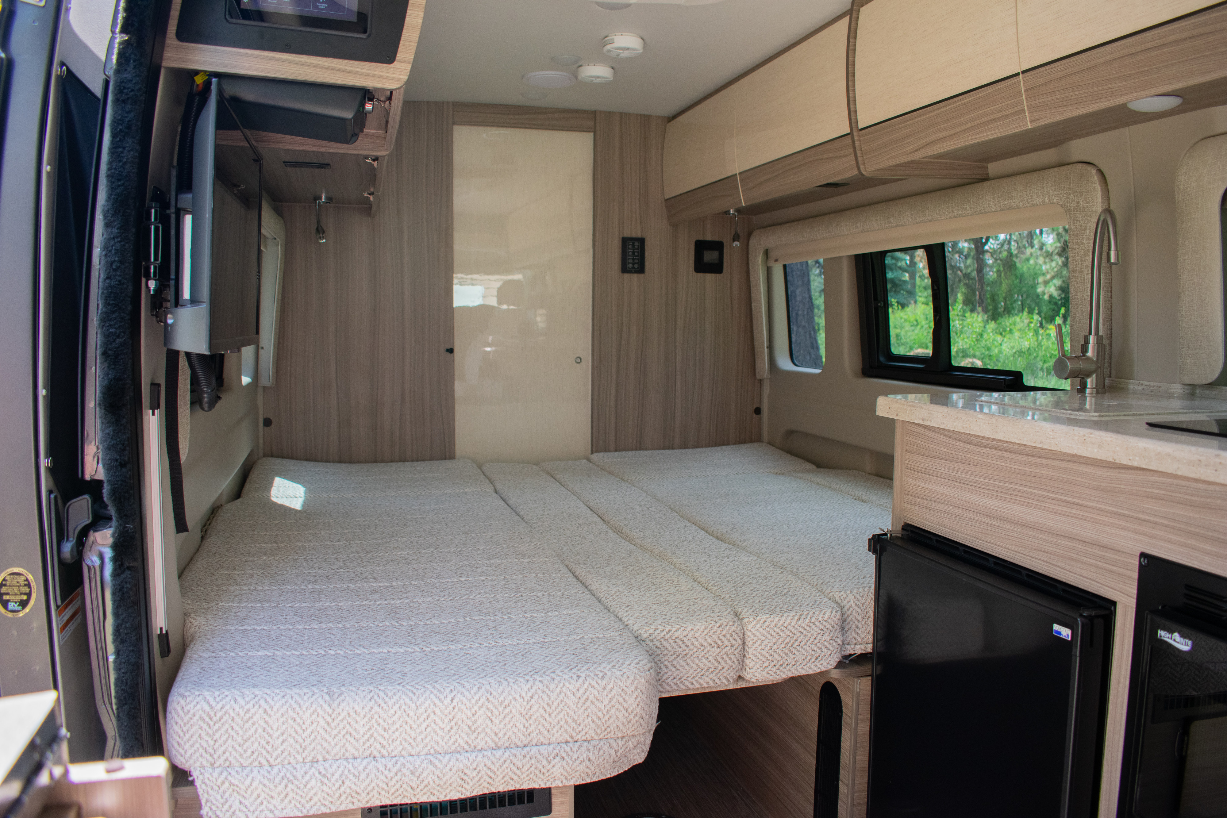 RV rental interior featuring a versatile bed, compact kitchen, and smart storage. Ready for your next travel adventure!. Entegra Coach Ethos 2023