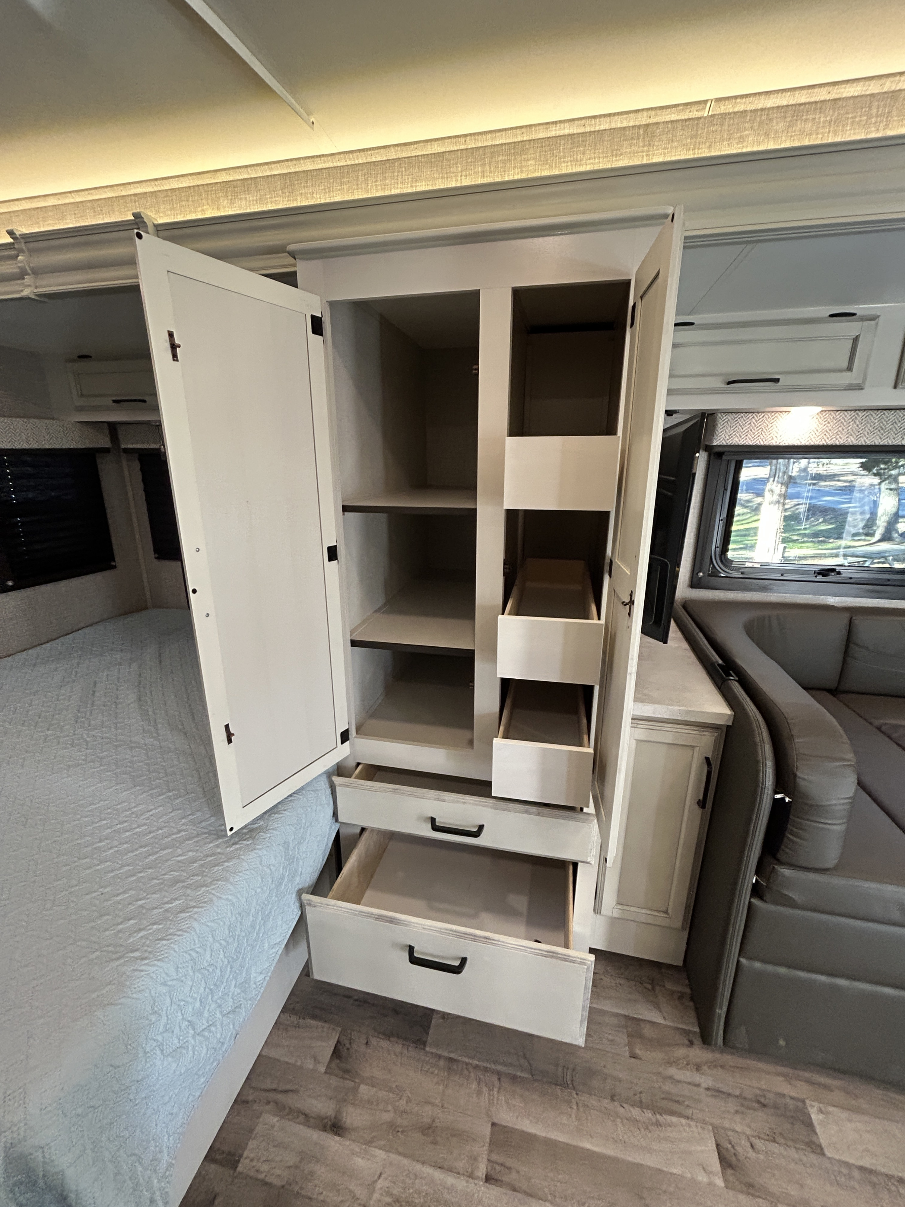 Explore this RV rental's clever storage: open wardrobe with shelves & pull-out drawers, plus bed & dinette.. Jayco Redhawk 2023