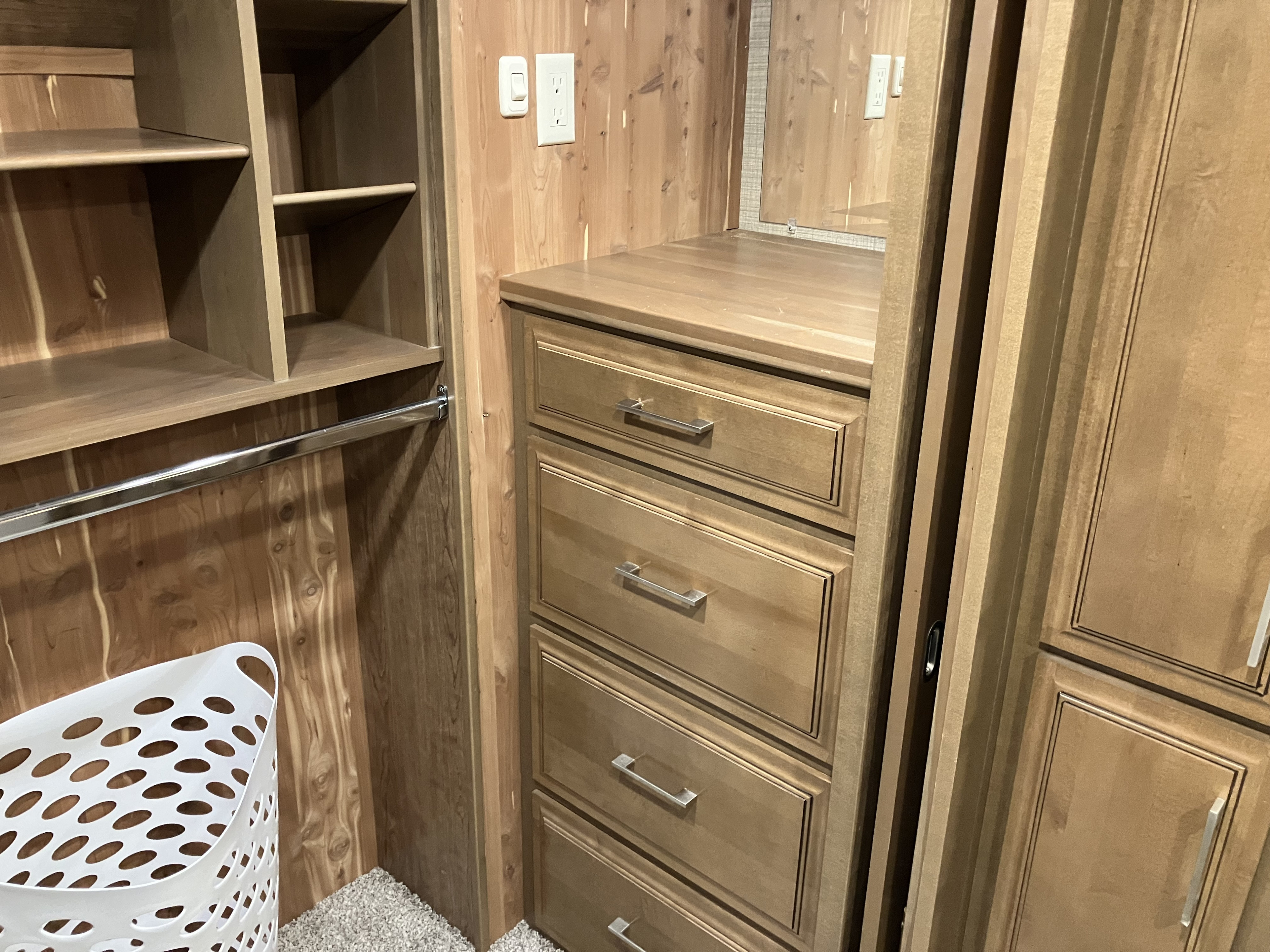 Spacious RV rental wardrobe with cedar lining, shelving, hanging rod, and ample drawers for organized storage.. DRV Mobile Suites 2018