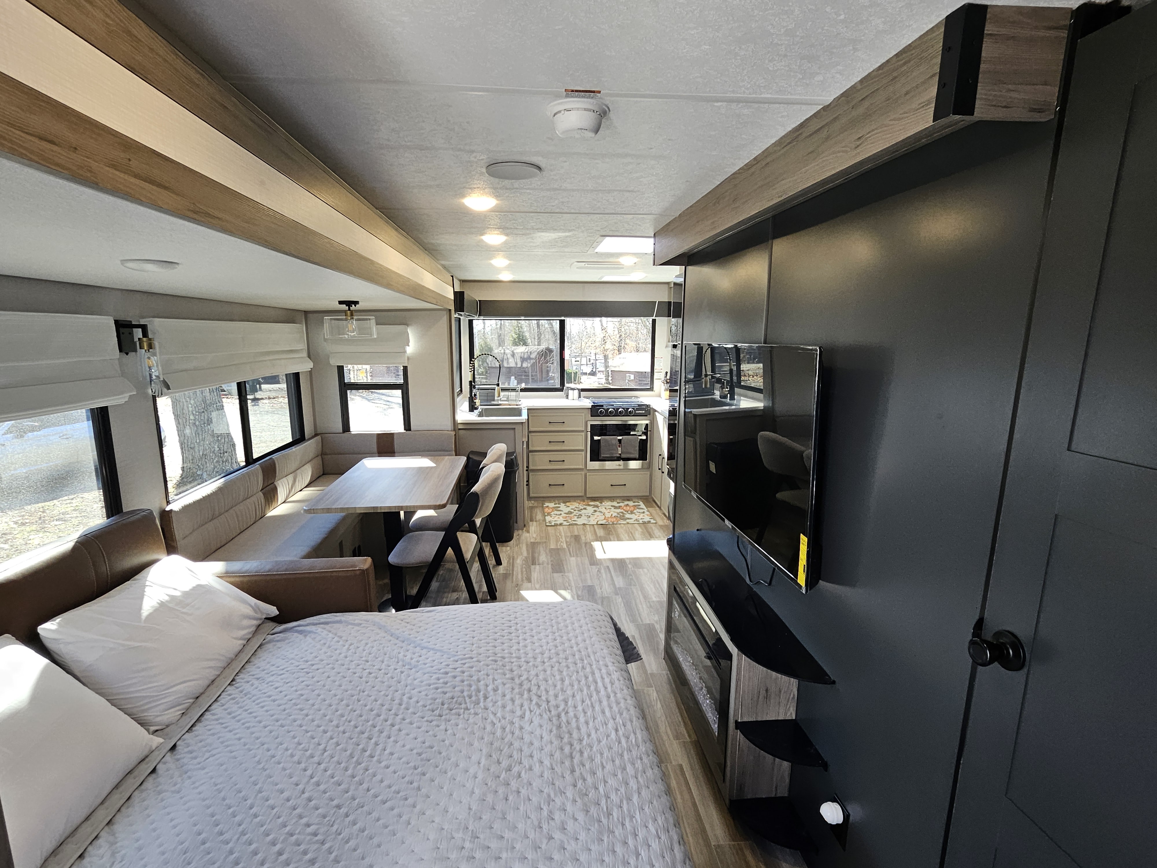 Spacious and modern RV rental interior featuring a comfortable bed, dining booth, full kitchen, and entertainment center.. Forest River VIBE 3400SB 2025
