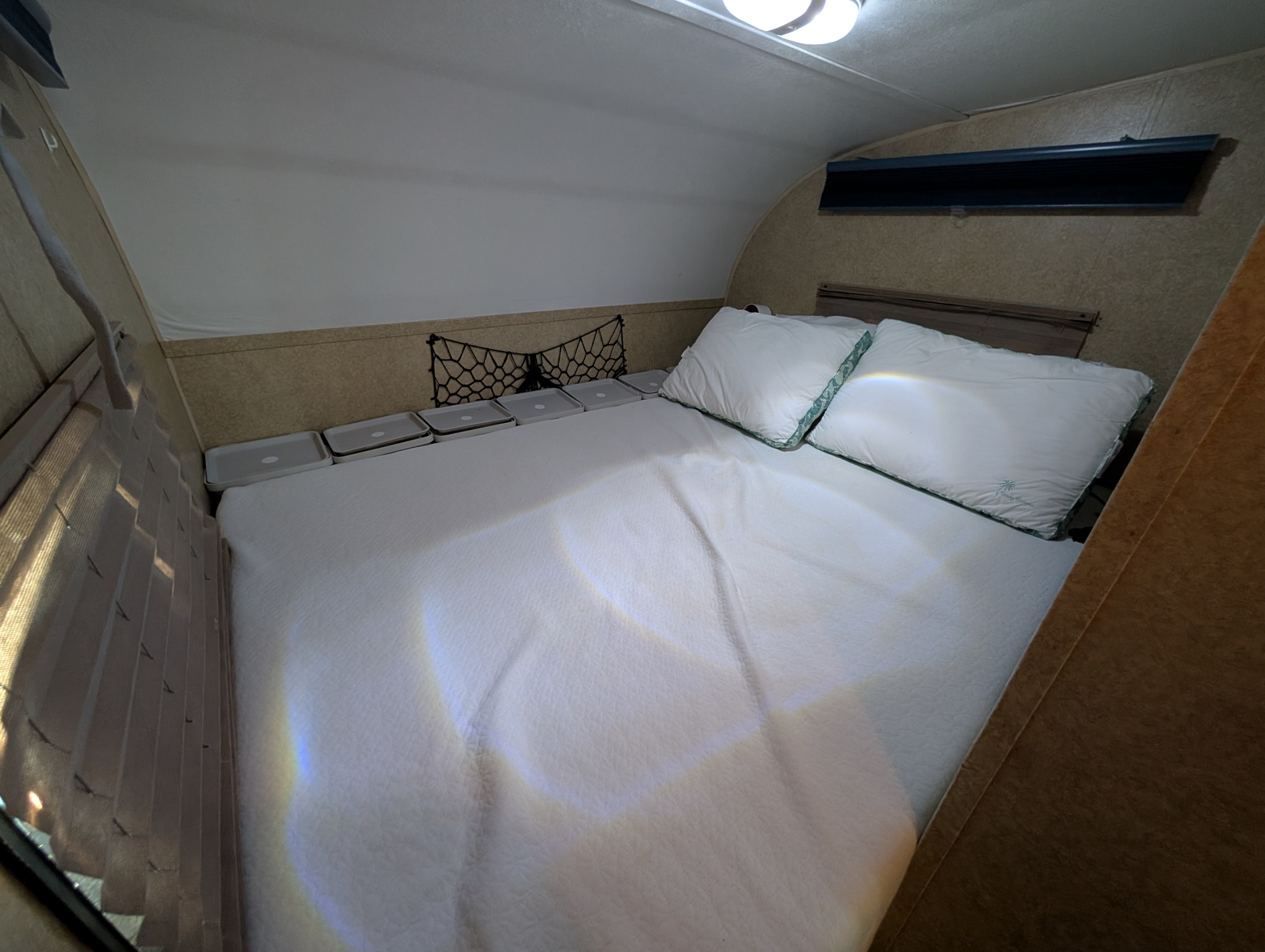 Inside an RV rental: A comfortable sleeping area with white bedding, pillows, and clever built-in storage for compact living.. Forest River V-Cross Vibe 2012