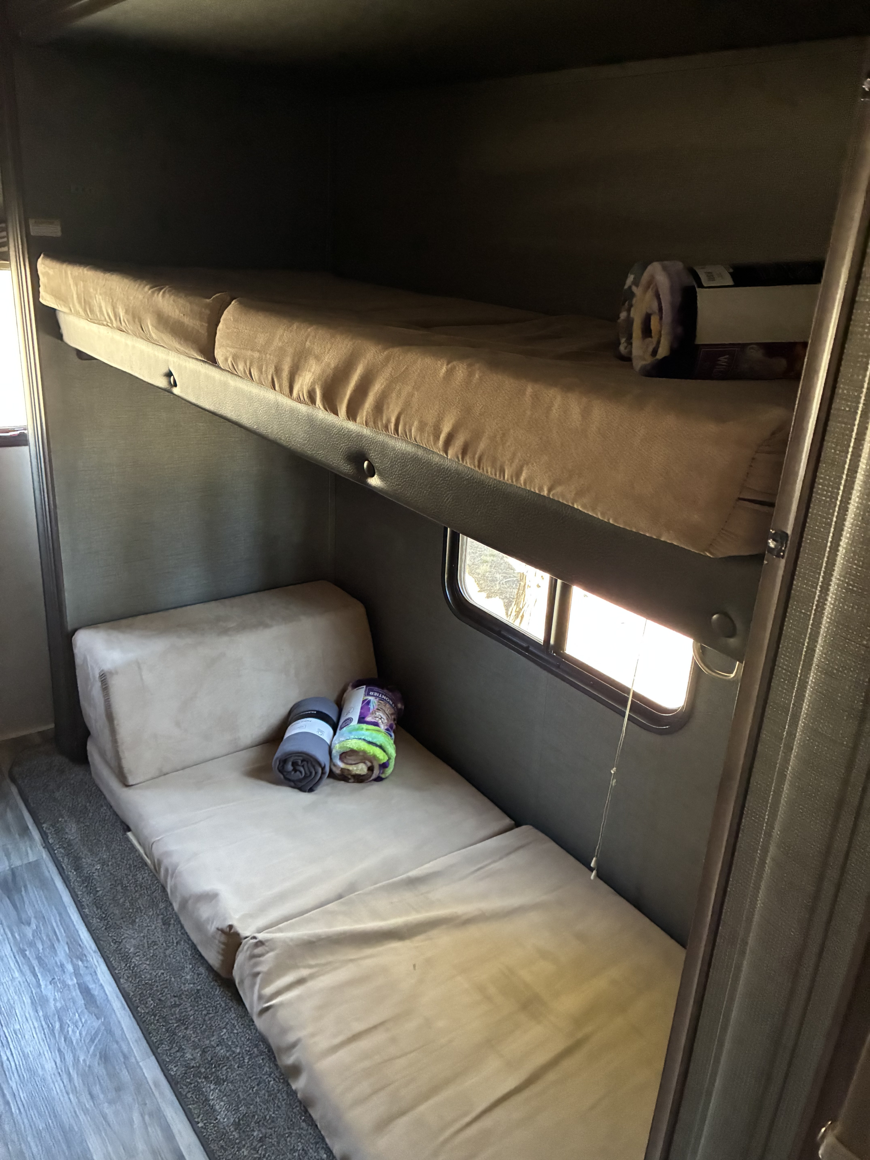Cozy RV rental interior with bunk beds, including a top bed and a lower convertible mattress.. Keystone Hideout 2019