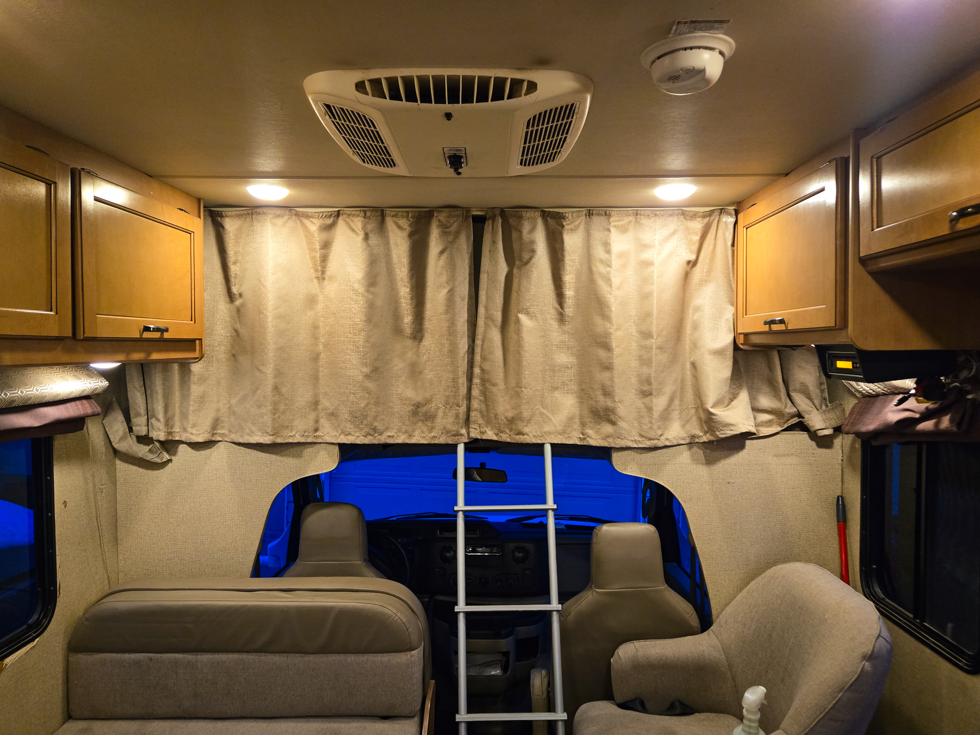 Experience comfort in this RV rental interior: overhead cabinets, AC, smoke detector, and a ladder to the cab-over bunk.. Thor Four Winds 2018