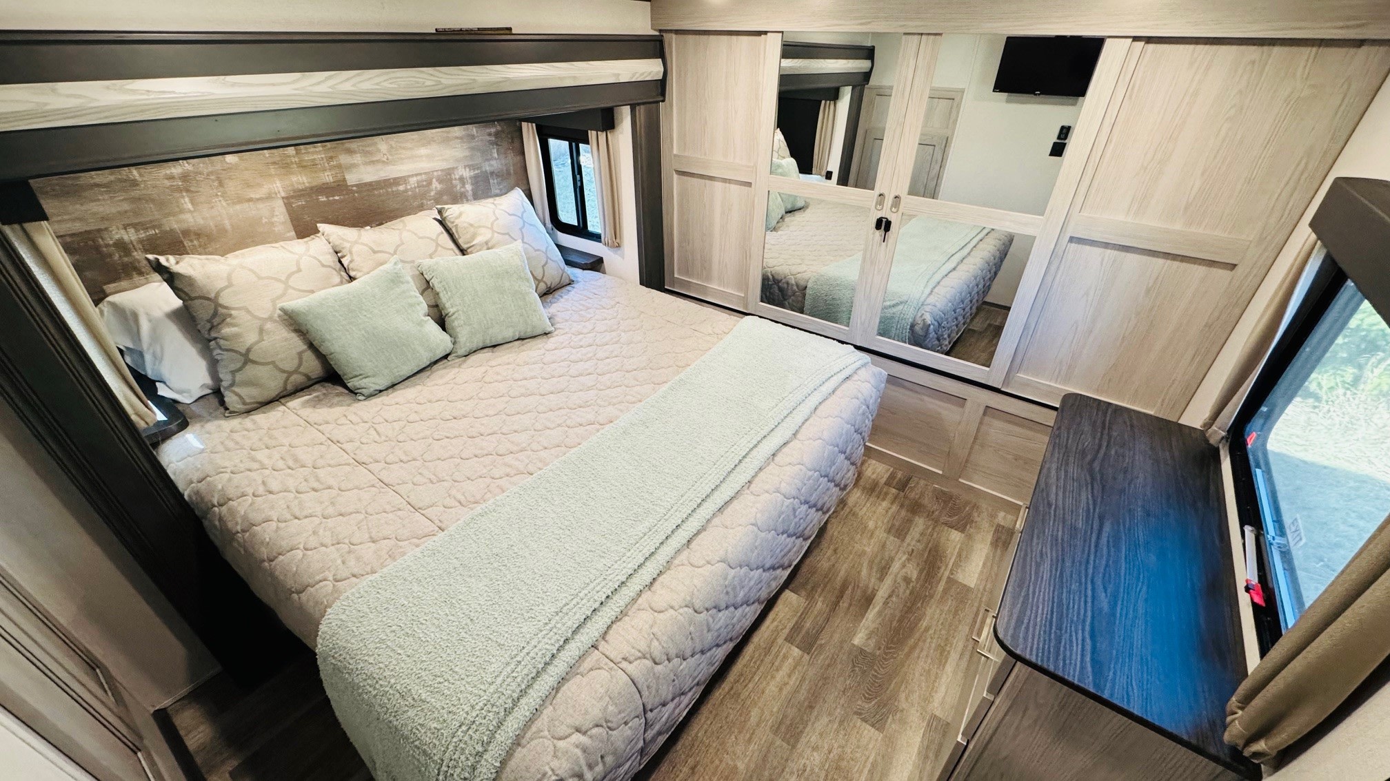 Cozy RV rental bedroom with a large bed, mirrored closet, and wood accents, perfect for comfortable travel.. Keystone RV Montana High Country 2021