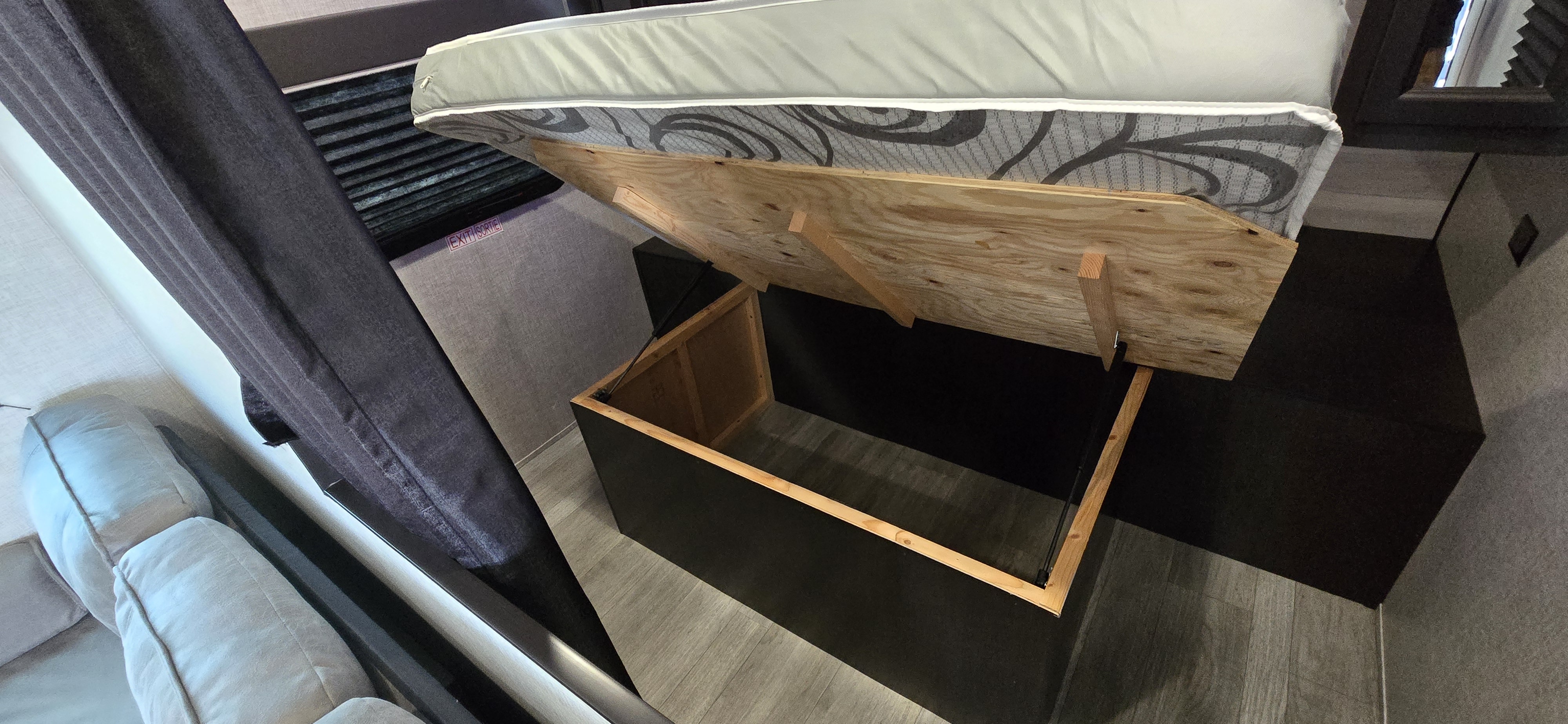 RV rental: Maximizing space with under-bed storage. This RV shows the mattress lifted, revealing a deep wood-lined bin.. Jayco Jay Flight SLX 2022