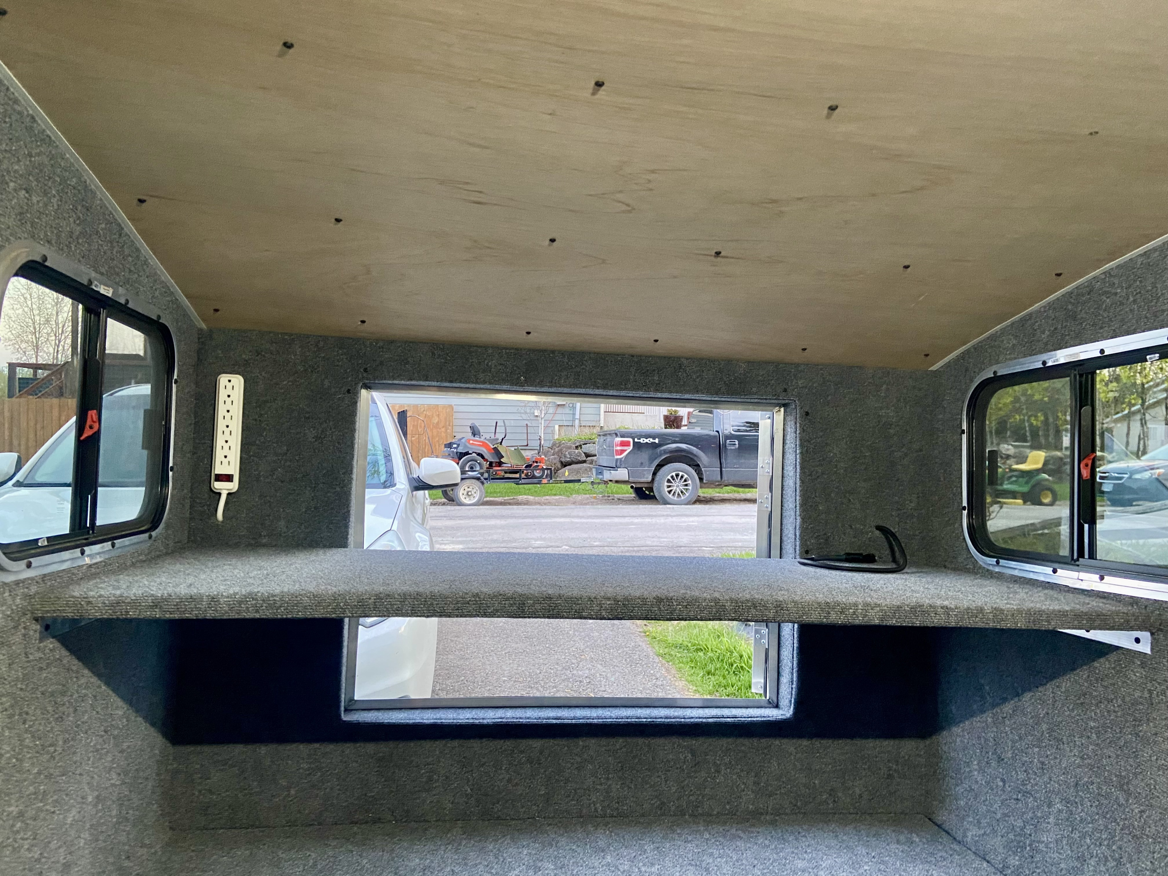 Inside an RV rental: a cozy space with carpeted walls, wooden ceiling, power strip, and scenic views from multiple windows.. Sherpa Bigfoot 5x8 2020