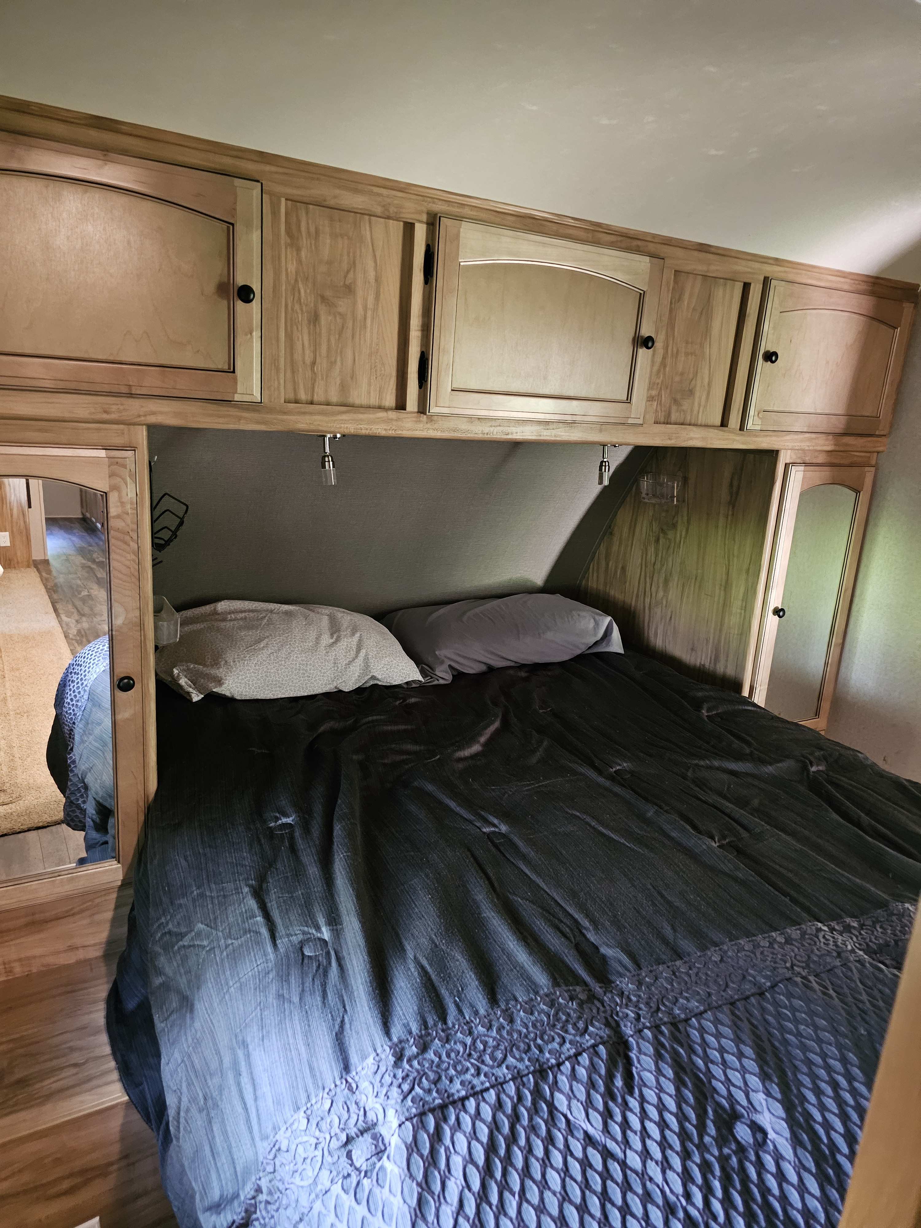 Inside an RV rental: cozy bedroom featuring a dark bed, wooden overhead cabinets, and convenient reading lights.. Coachmen Freedom Ultralite Express 2018