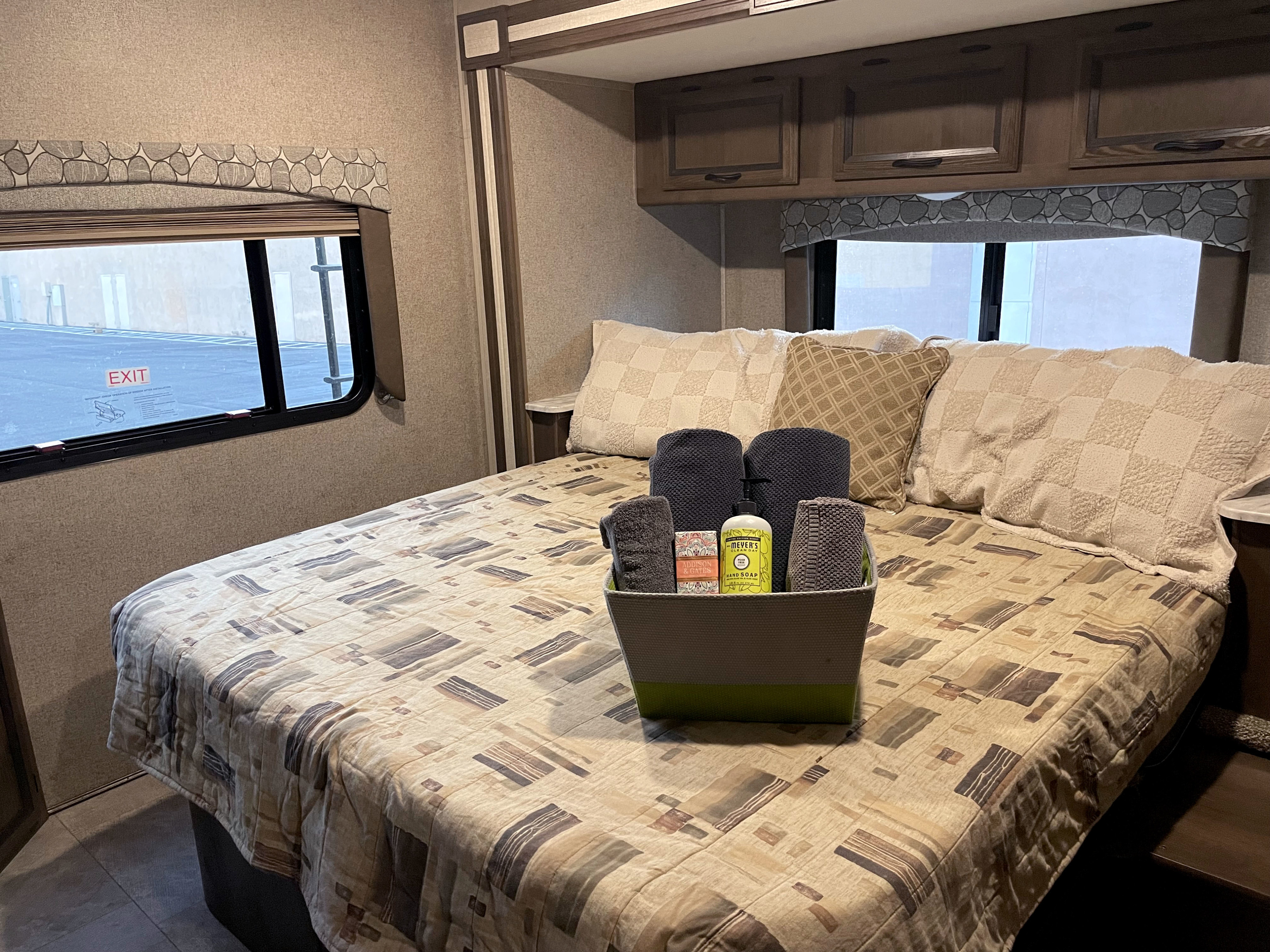 Cozy rv rental bedroom featuring a comfortable bed with a patterned comforter, pillows, and a welcoming basket of amenities.. Forest River Coachmen Freelander 2019