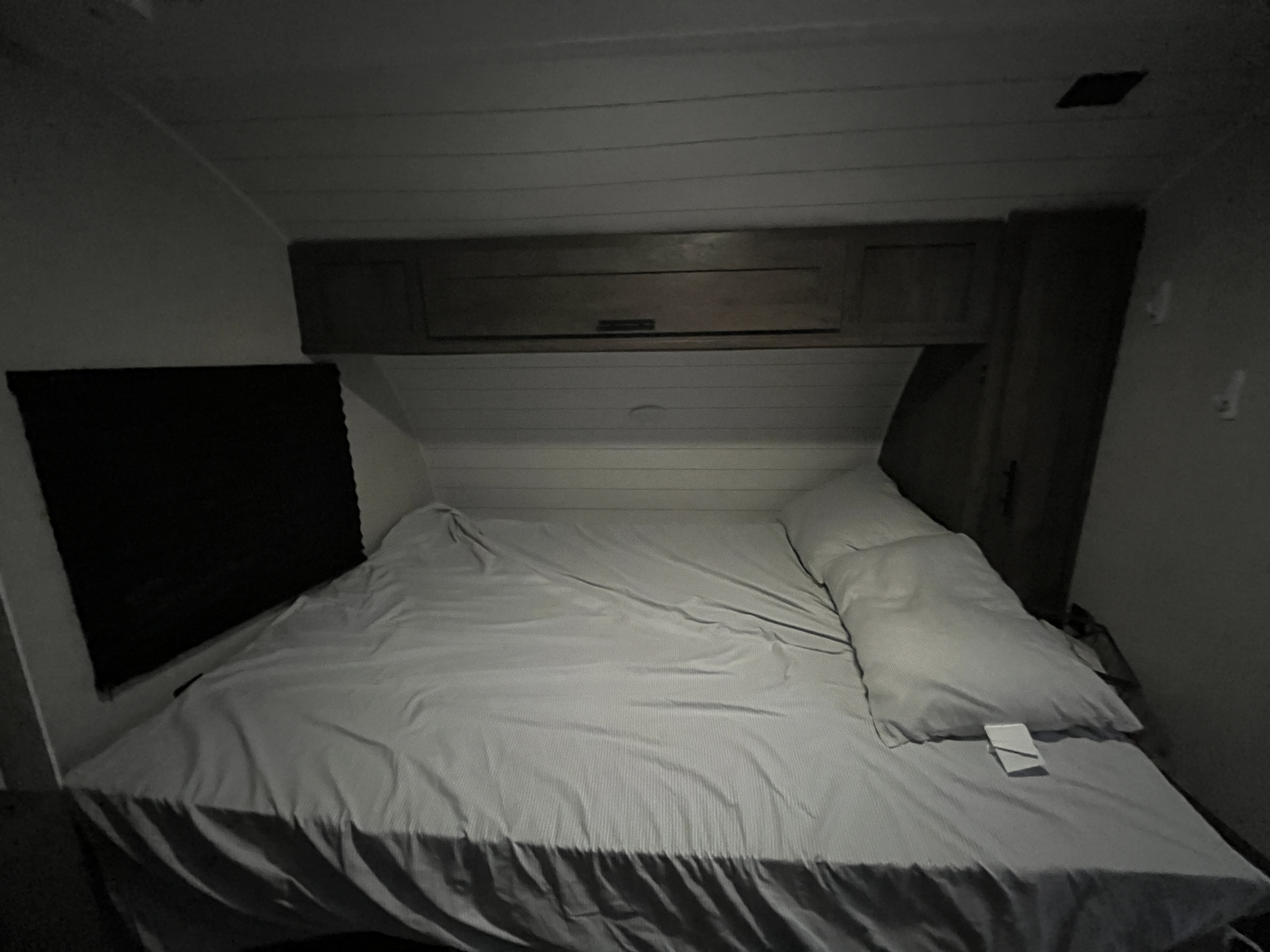 Cozy RV rental bedroom with a striped bedspread, overhead cabinets, and dark window shade for a comfortable travel stay.. Forest River EvoFS 2021