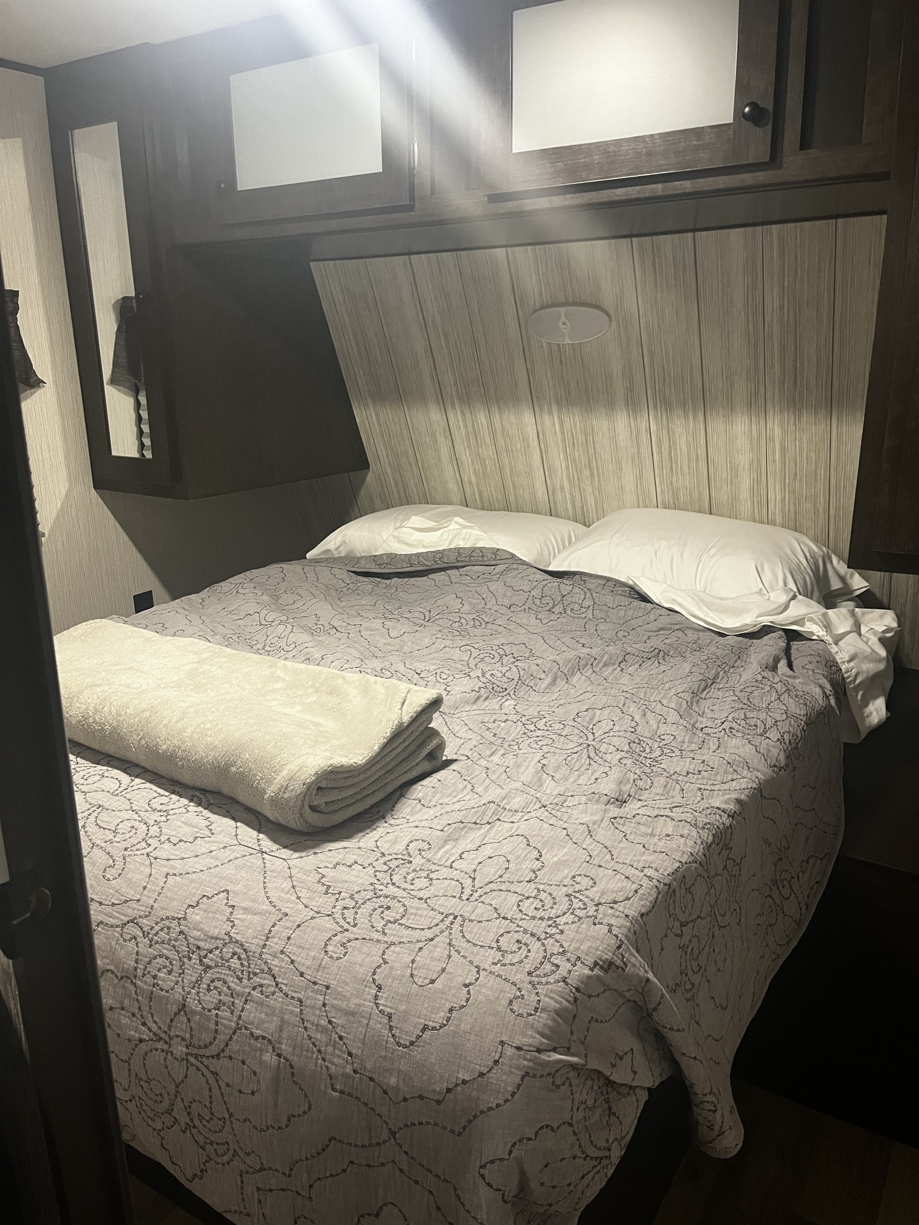 Comfortable RV rental bedroom interior with a patterned comforter, white pillows, and overhead storage, offering a cozy space.. Heartland RVs Pioneer 2020
