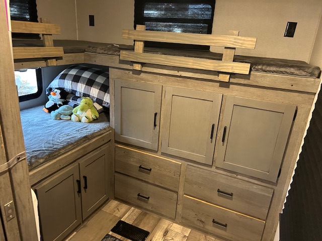 RV rental family bunk beds with built-in storage. Stuffed animals & pillow on lower bed.. Keystone RV Outback Ultra-Lite 2021