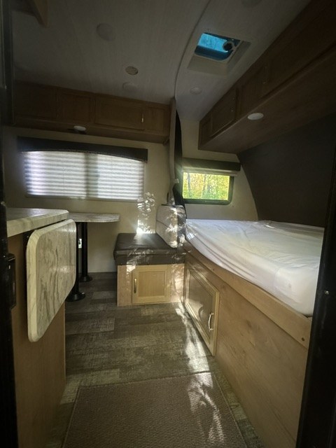 Compact rv rental interior with a cozy bed, dinette, storage, and natural light from windows.. Winnebago Micro Minnie 2020