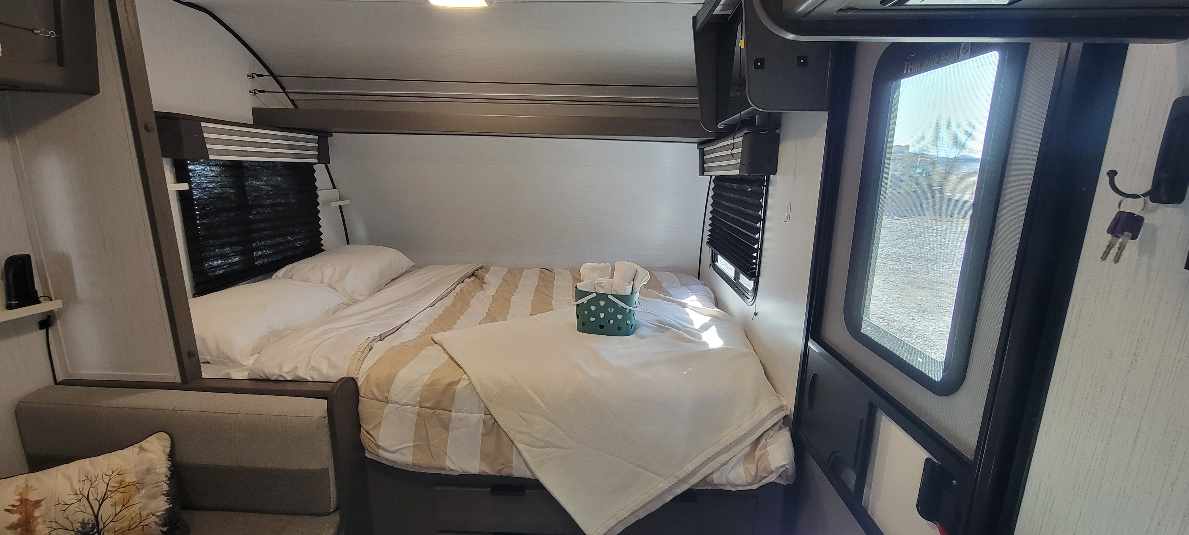 RV rental's cozy interior: a compact bedroom with a comfy bed, mounted TV, and window views.. Heartland RVs Mallard Pathfinder 2022