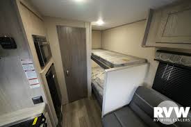 Compact RV rental interior: bunk beds, sofa, & kitchen appliances, ideal for family travel.. Coachmen 164BHX 2023