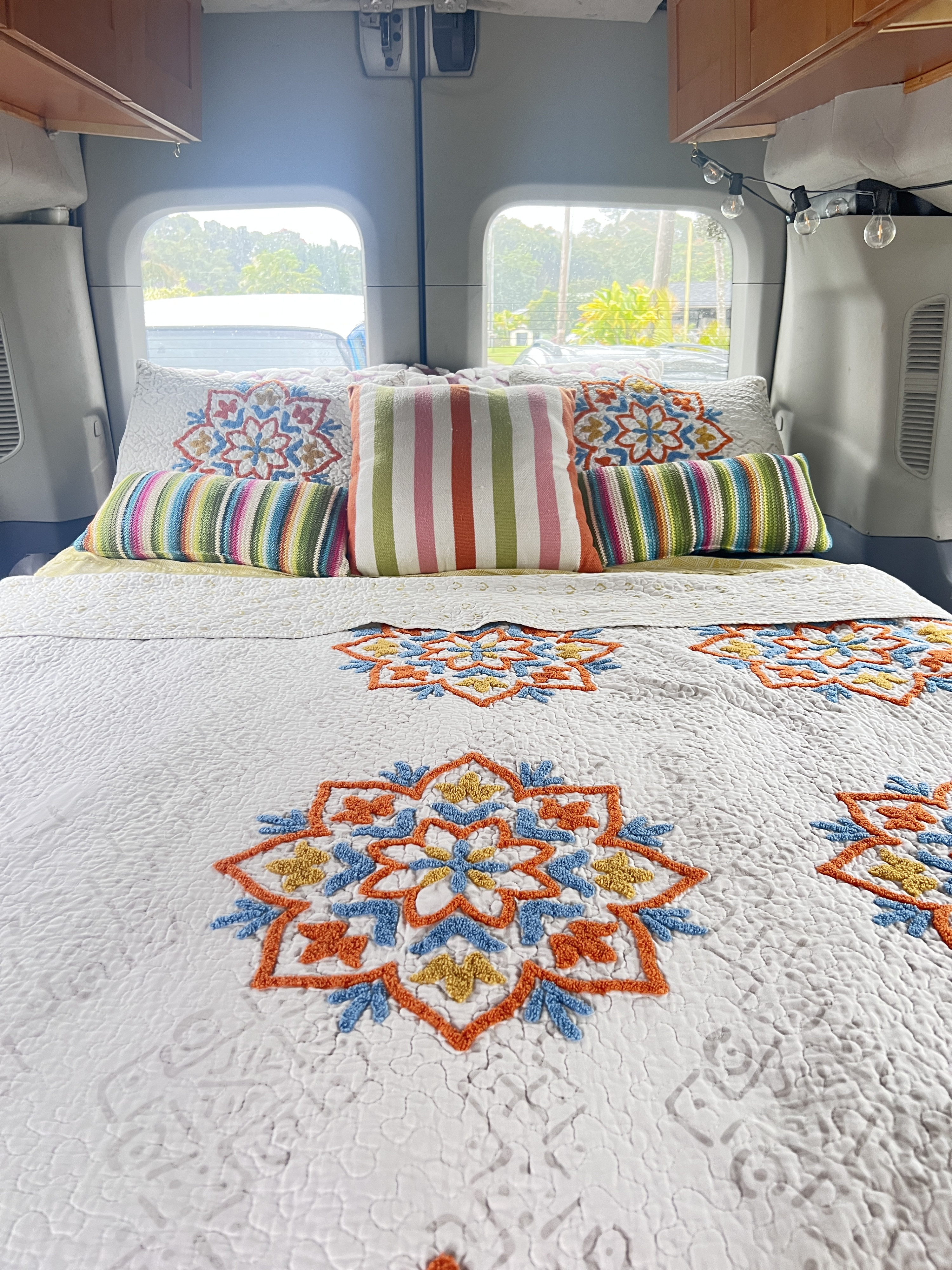 This RV rental offers a stylish, comfy bed featuring a white quilt with colorful mandalas and striped pillows.. Ford Transit Custom 2016