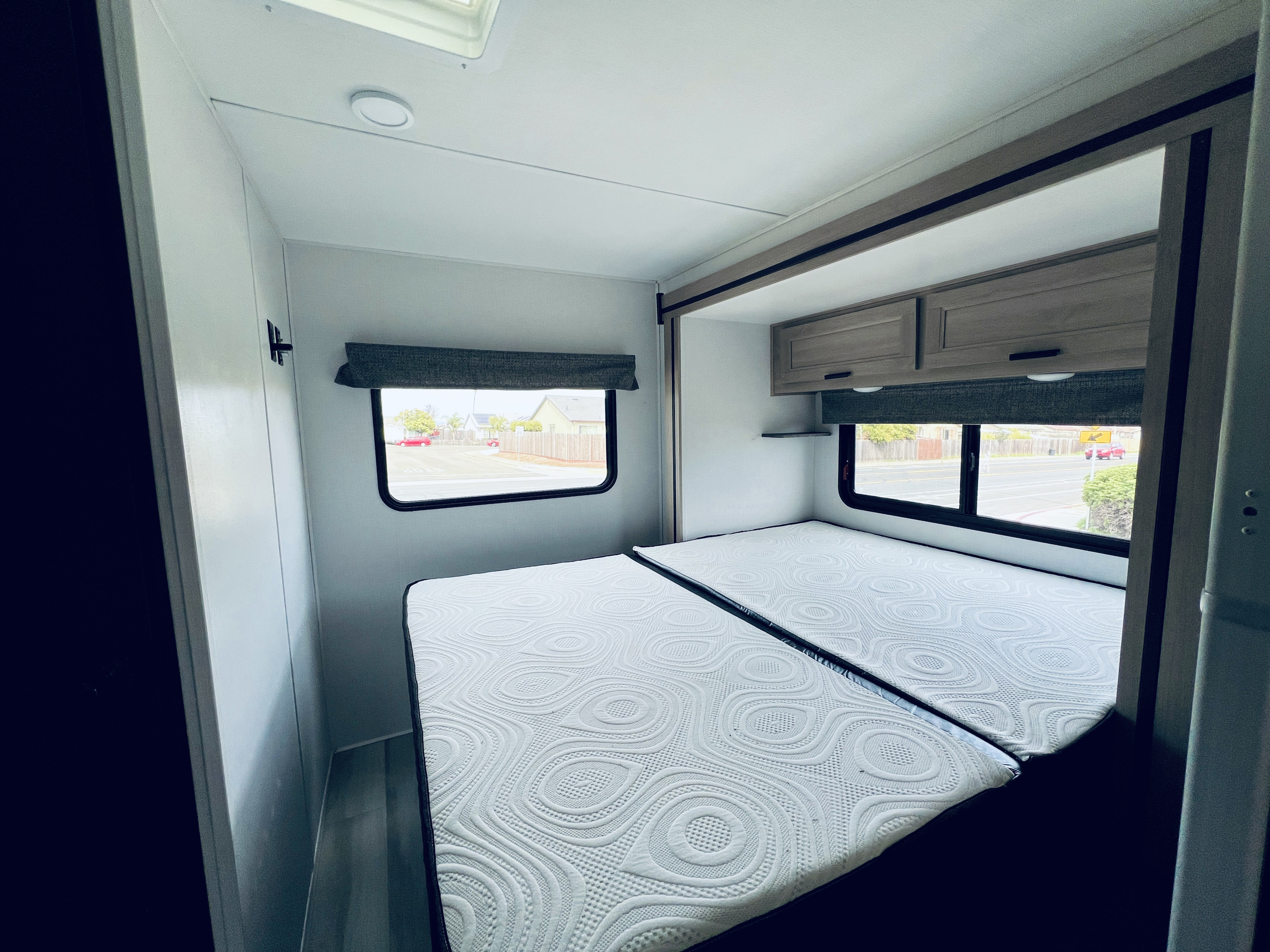 Spacious RV rental bedroom with two comfortable mattresses, overhead cabinets, and windows offering street views.. FOREST RIVER FORESTER 2251 SLE 2025