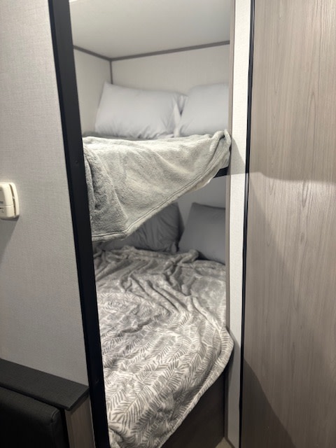 Neat, stacked bunk beds inside an RV rental. Both bunks are made with blankets and pillows, ready for your trip.. Coleman Lantern 2024