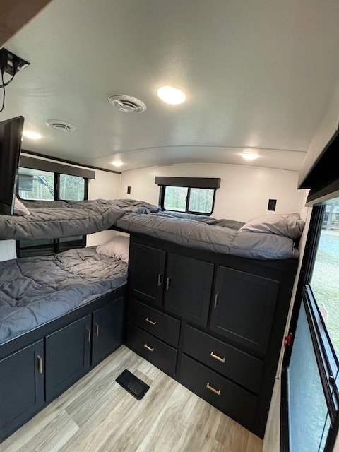 RV rental featuring modern bunk beds, sleek black built-in storage, and wood-look flooring in a clean interior.. Keystone RV Outback Ultra-Lite 2022