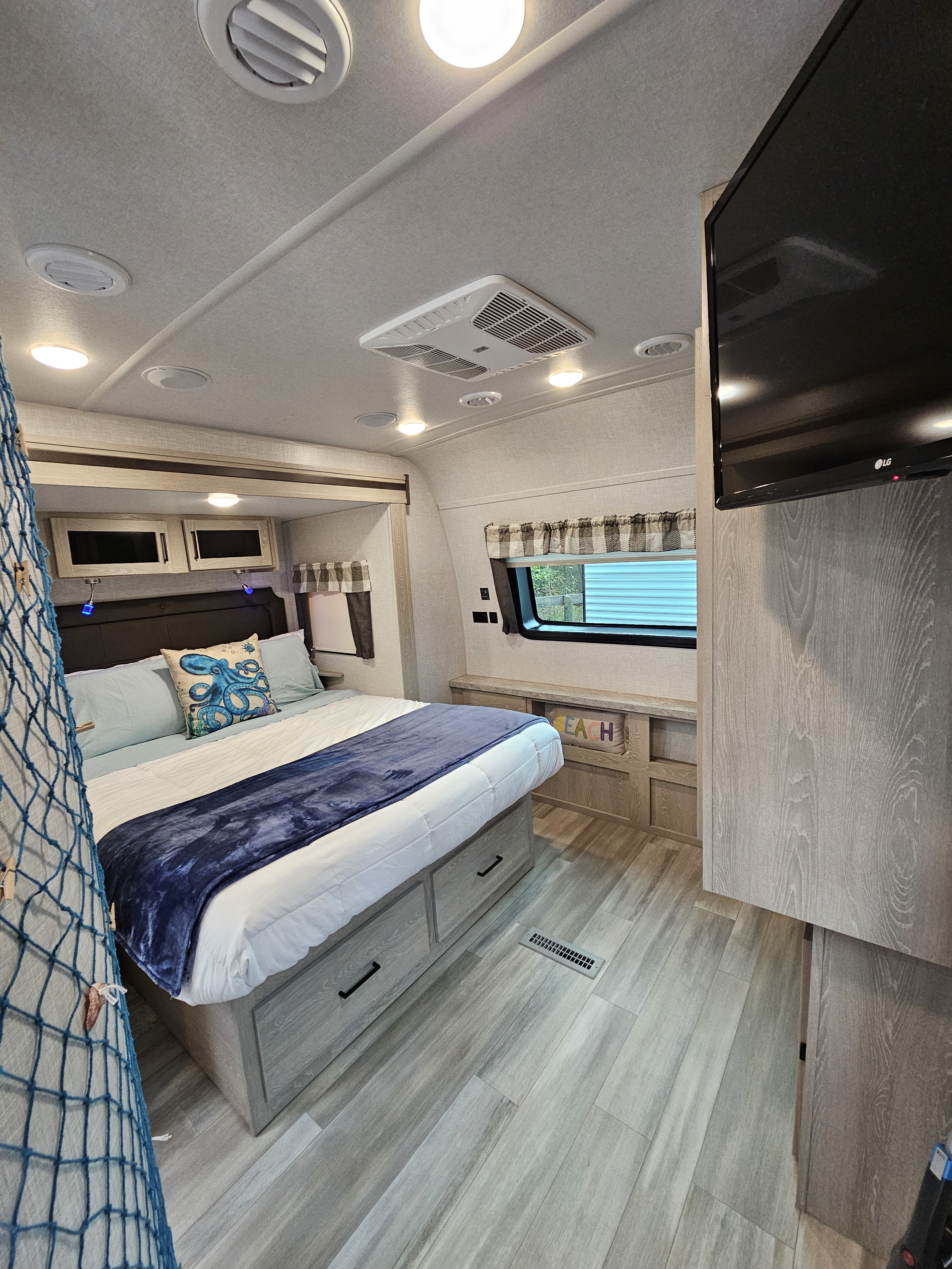Spacious RV rental bedroom with a comfortable bed, overhead cabinets, TV, and beach-themed decor for your journey.. Flagstaff Other 2021