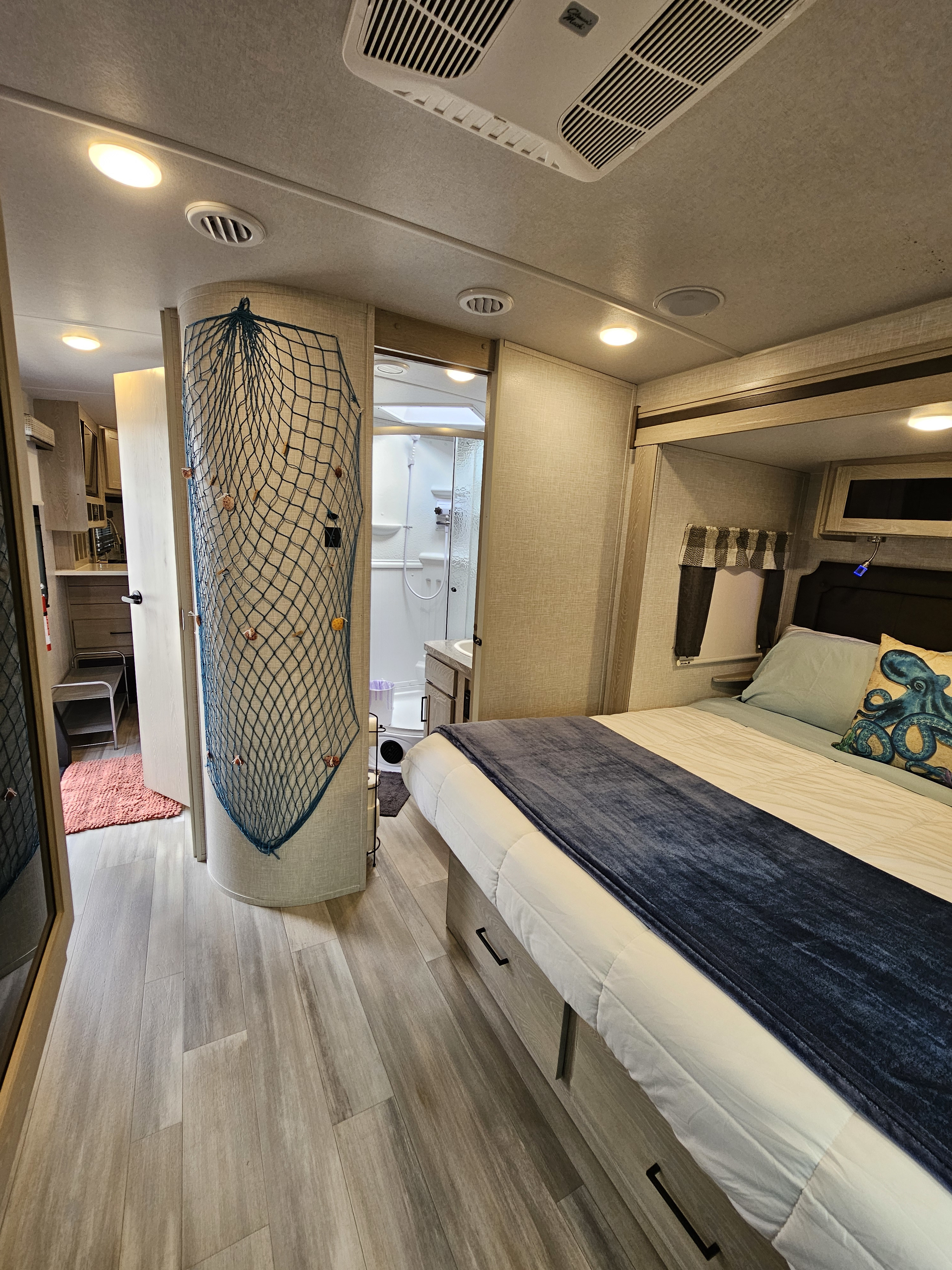 Interior of an RV rental: bedroom with nautical decor, adjacent bathroom, and wood-look flooring.. Flagstaff Other 2021