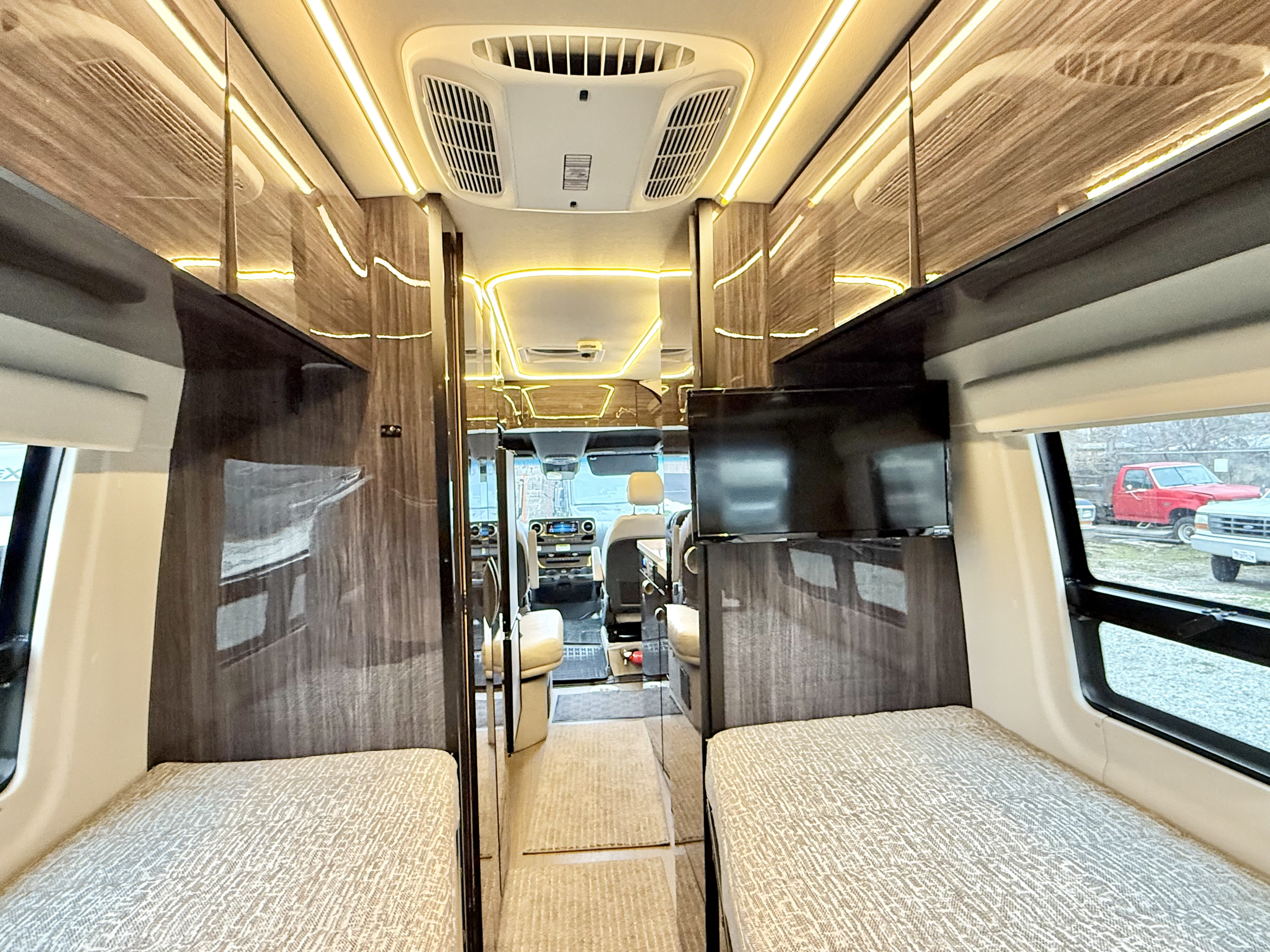 Inside a sleek rv rental, featuring twin beds, bright ambient lighting, AC, and front cabin access for comfortable travel.. Winnebago Era 2020