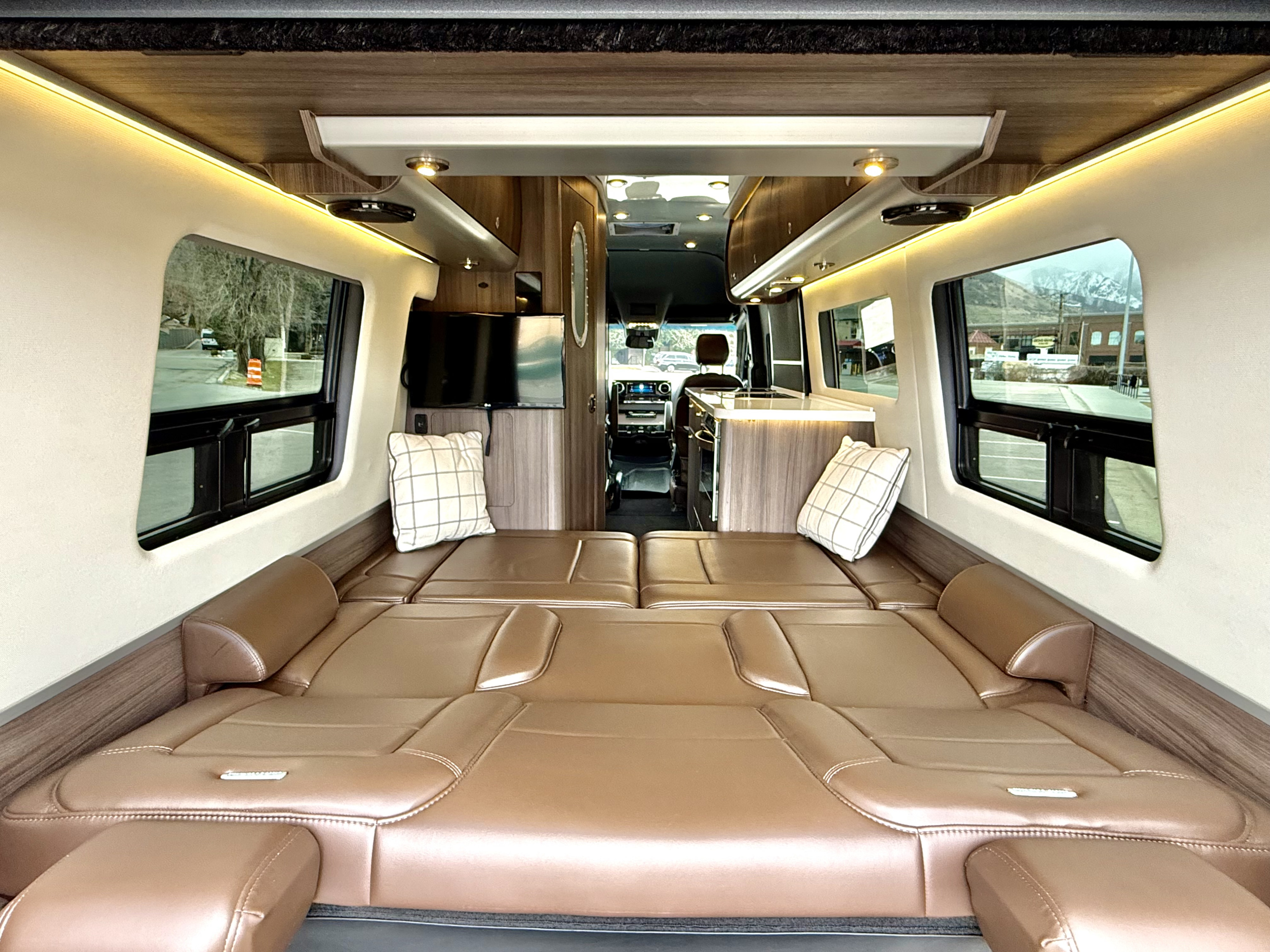 Inside a luxurious rv rental, featuring plush seating converting to beds, a compact kitchen, & panoramic windows.. Airstream Interstate 2021