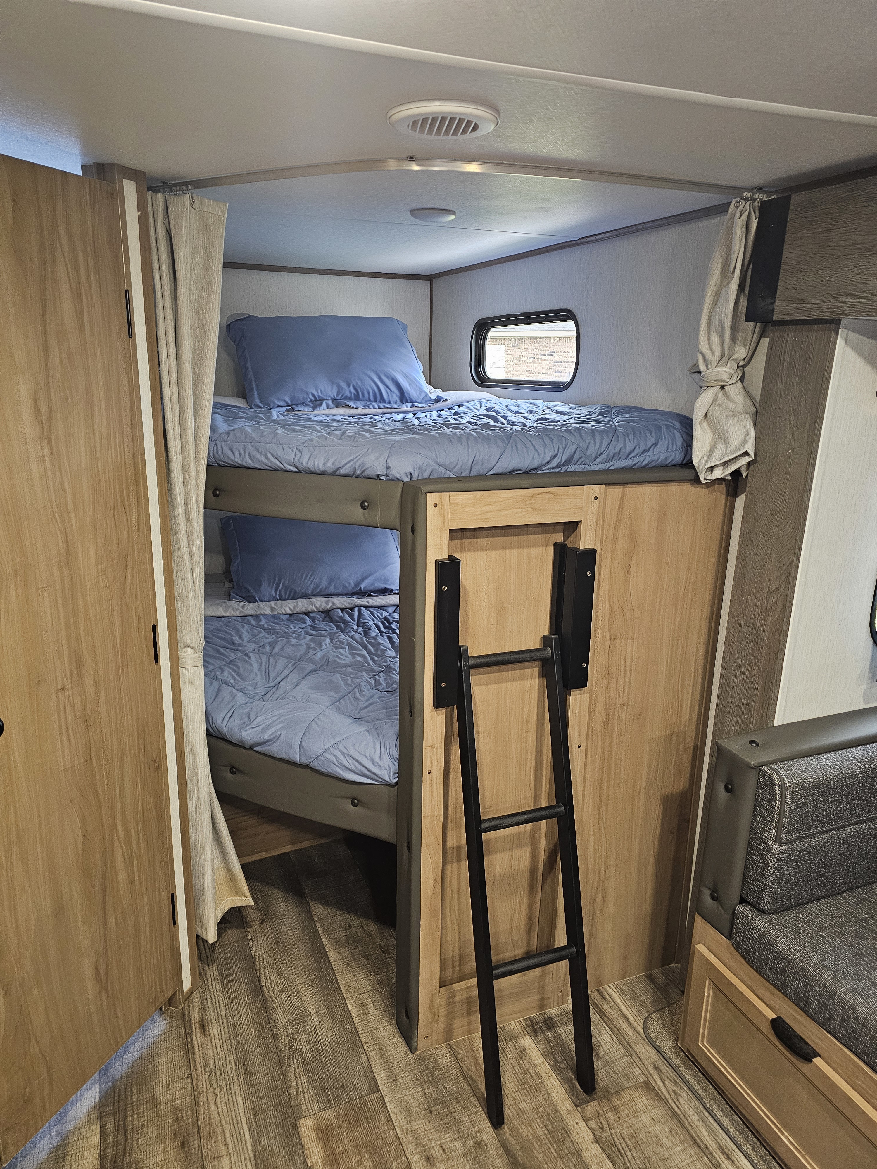 Explore this RV rental's sleeping area featuring comfortable bunk beds with blue bedding, a window, and a ladder.. Forest River Cherokee Alpha Wolf 2024