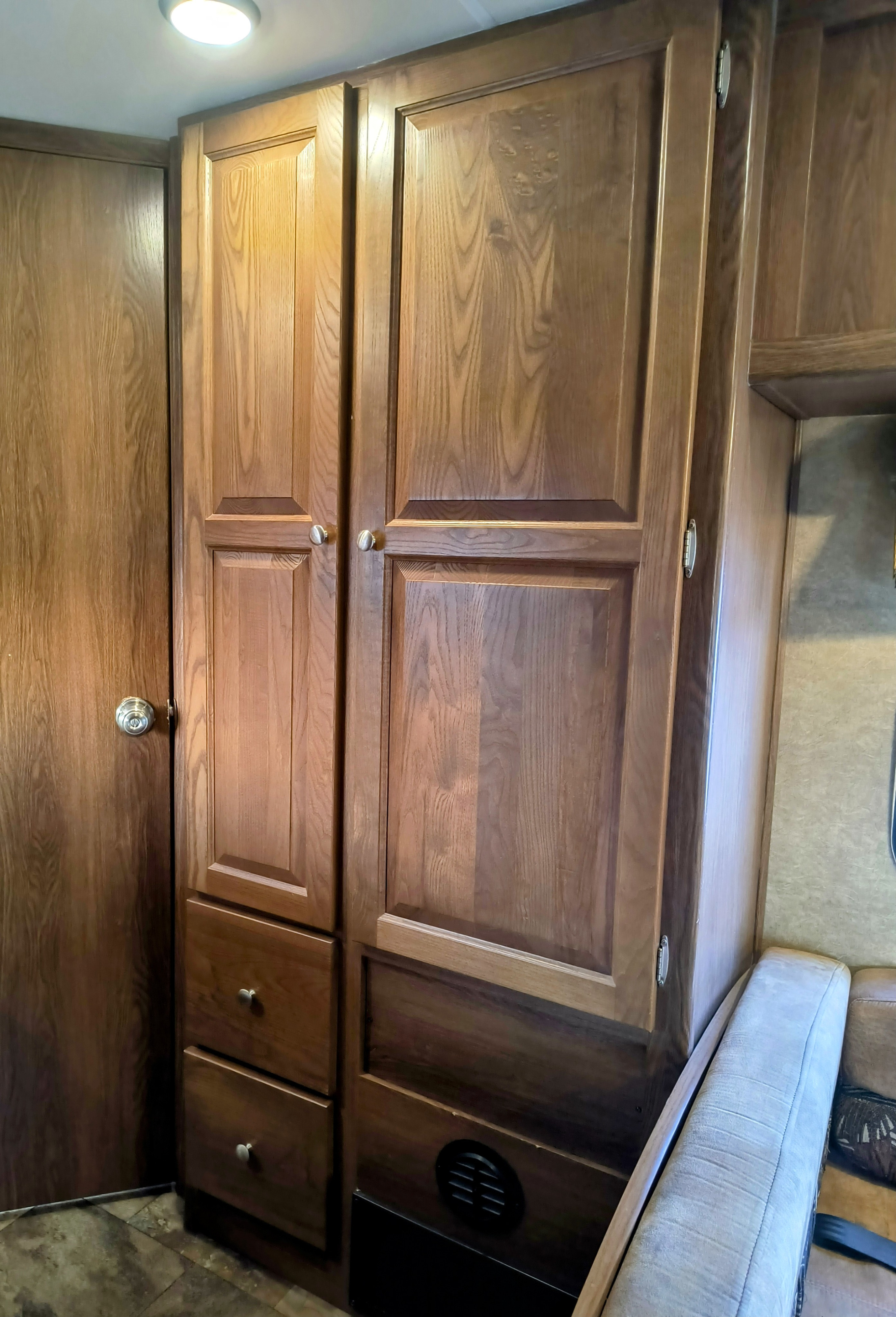 RV rental: Built-in wooden cabinetry, a door, and part of a sofa, providing storage in a compact RV living space.. Coachmen Leprechaun 2015