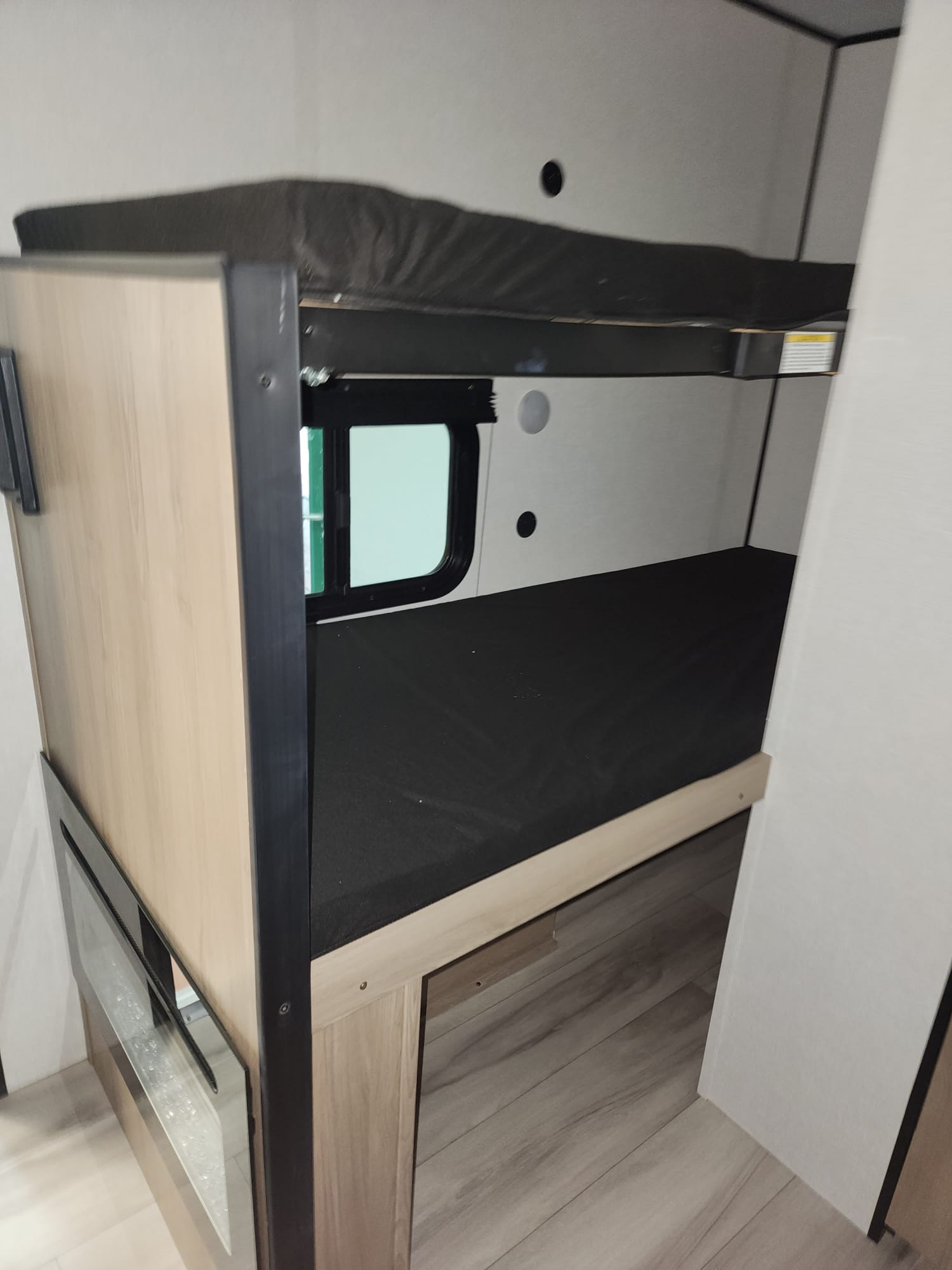 This RV rental features cozy bunk beds with mattresses, a small window, and wood-look flooring, ideal for a travel trailer.. Keystone Coleman 13B 2025