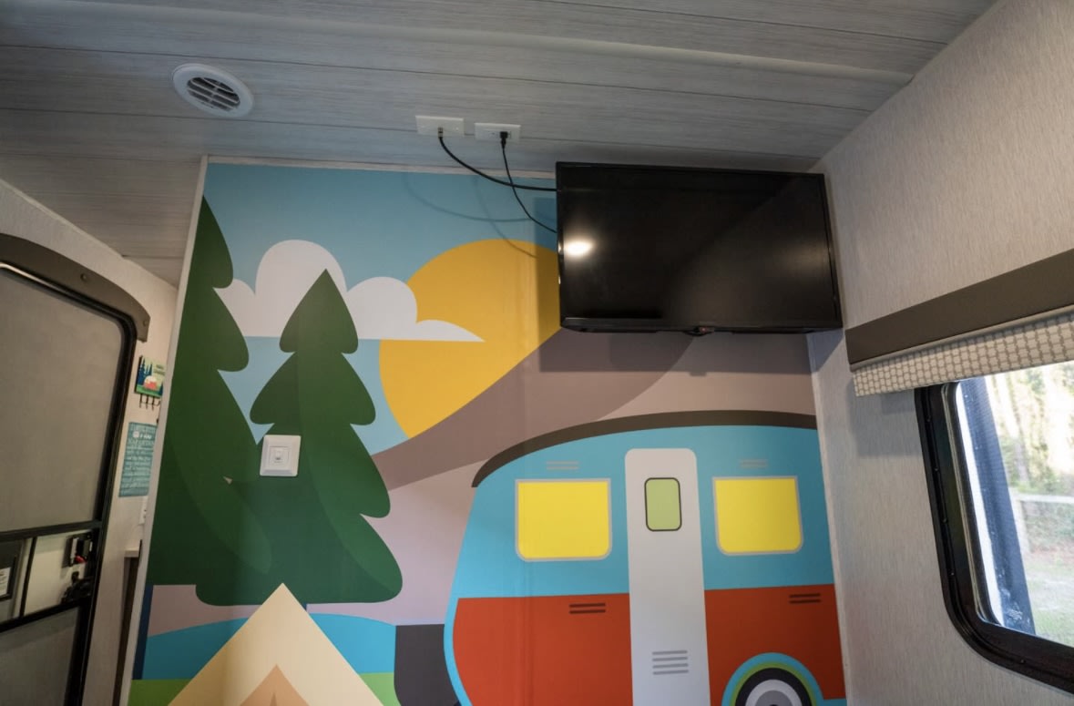 Fun RV rental interior with playful mural, TV, and ceiling vent. Perfect for family camping trips!. Forest River Salem 2022