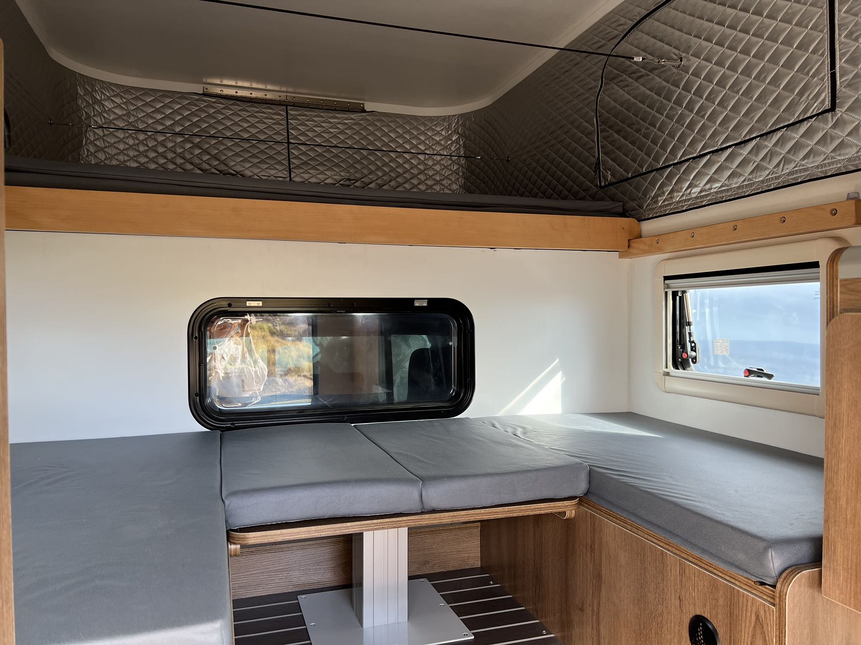 Cozy RV rental interior with convertible bed, upper bunk, and large windows, designed for comfort on the go.. toyota tacoma 2024