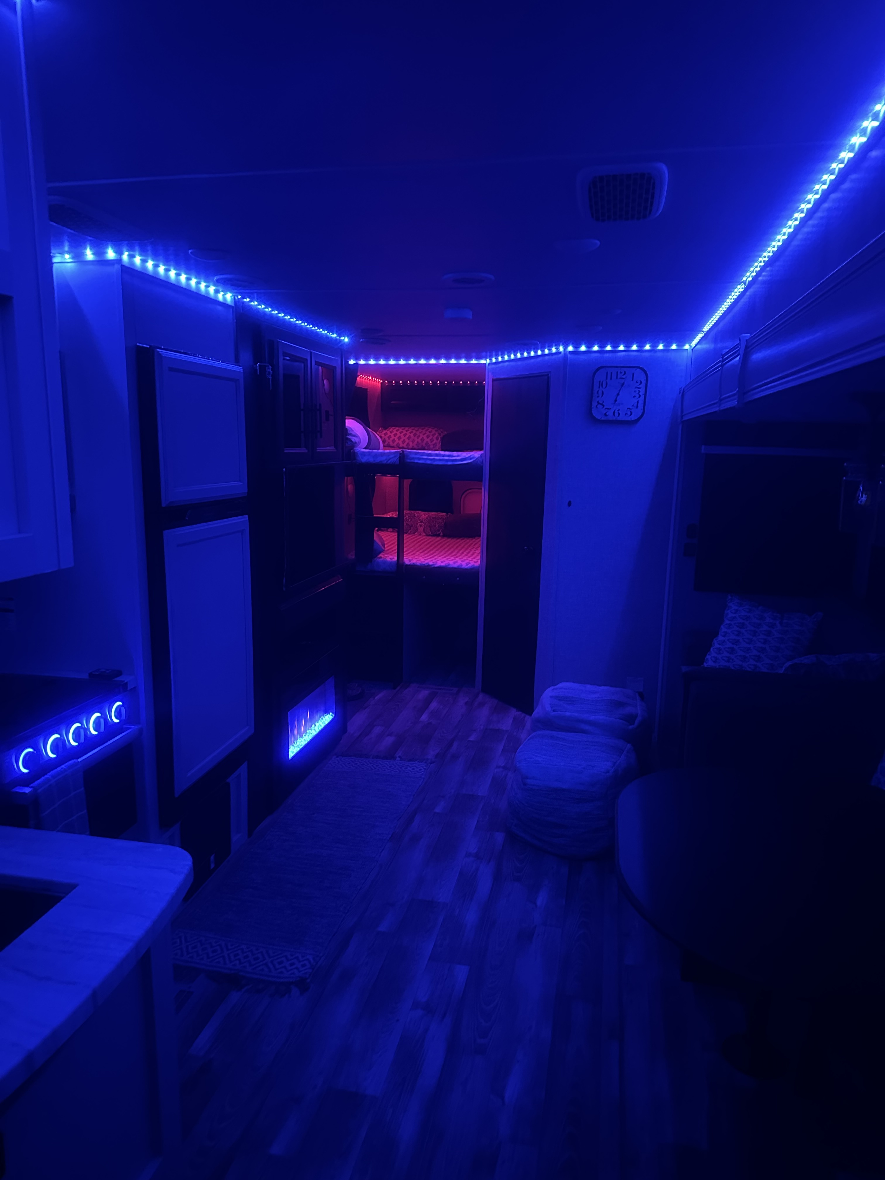 An RV rental's interior glows with blue LED strips, featuring cozy bunk beds with magenta lighting.. Jayco Eagle HT 2022