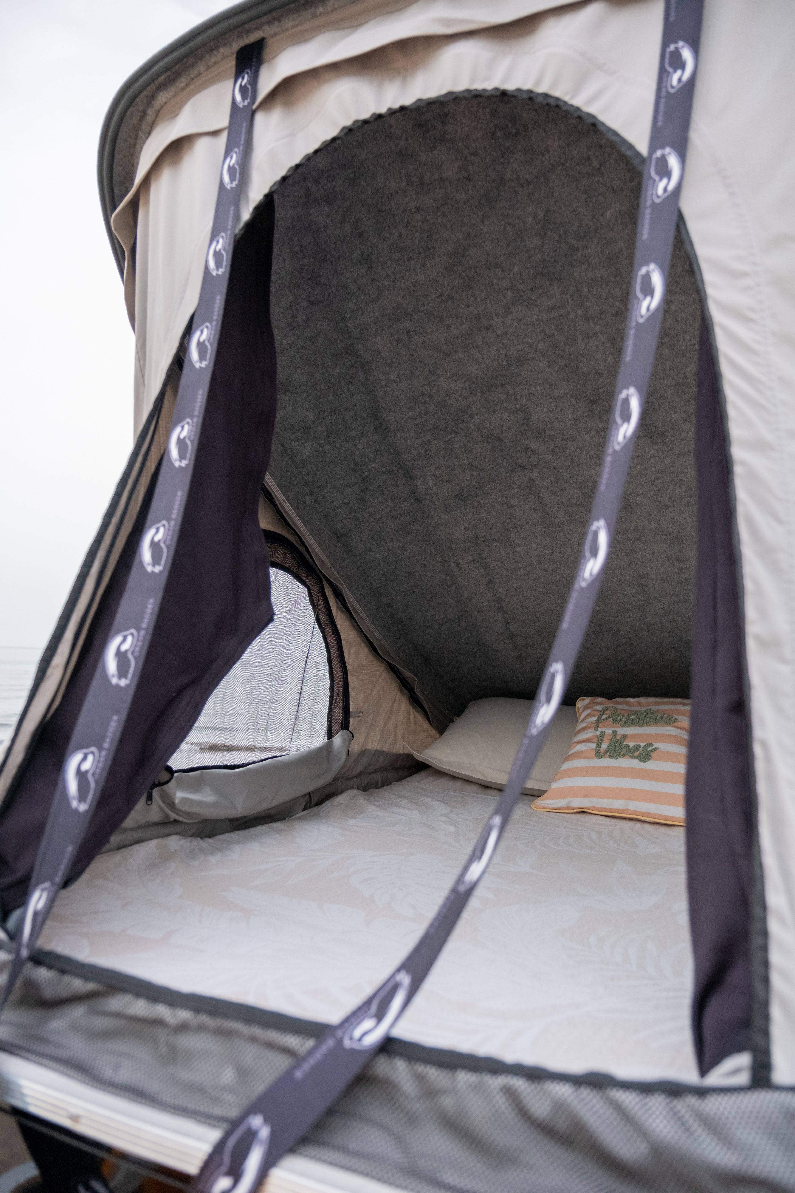 Inside a comfy rooftop tent from an RV rental, offering cozy bedding and a view of the water. Perfect for adventure.. Ford F-150 Gas / Propane Hybrid and Hotomobil Gladiator XL Extended with roof tent 2020