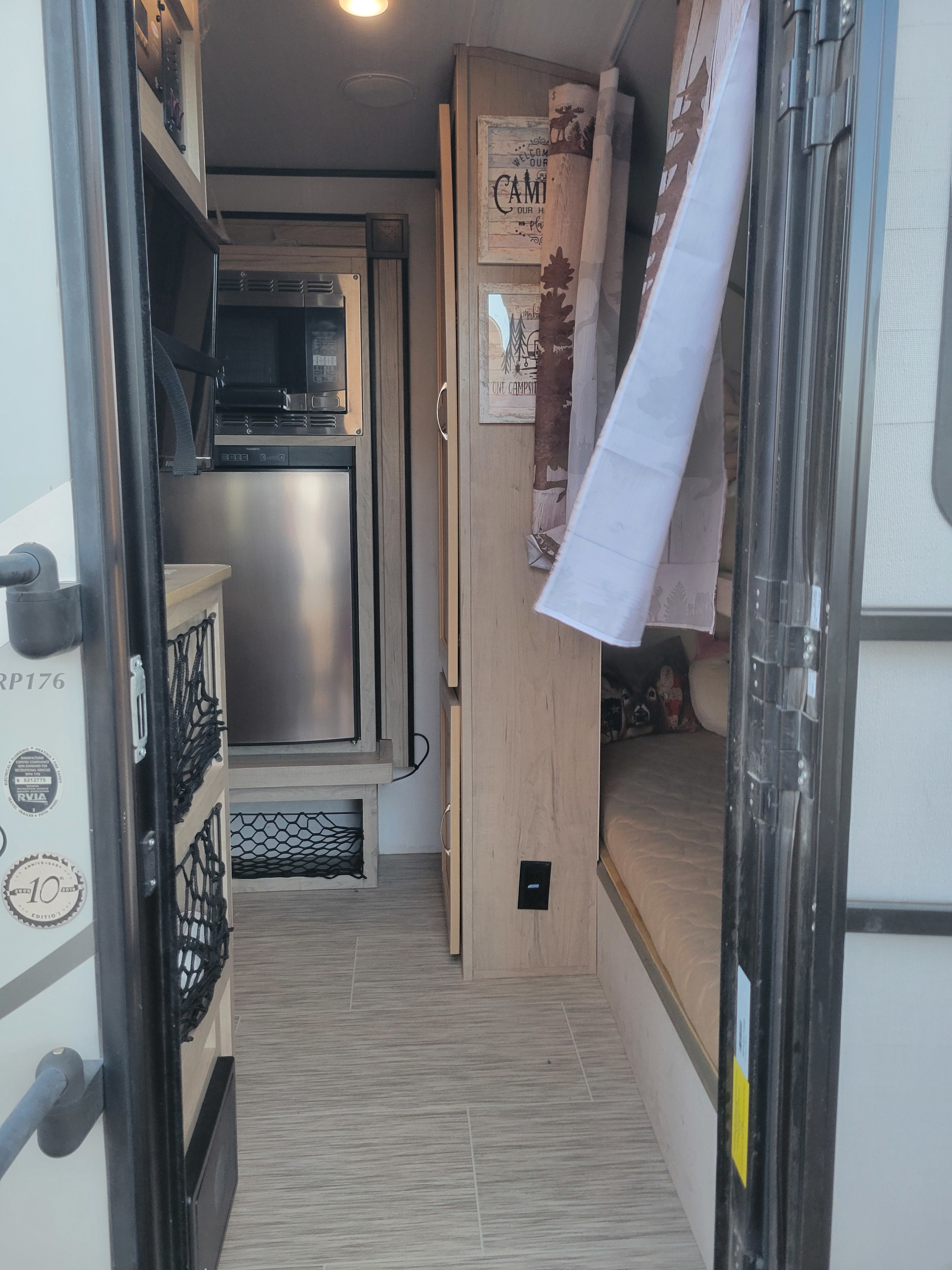 Modern RV rental interior with a compact kitchen, sleeping bunk, and rustic camping decor. Ready for adventure!. Forest River RPT-176 47 2018